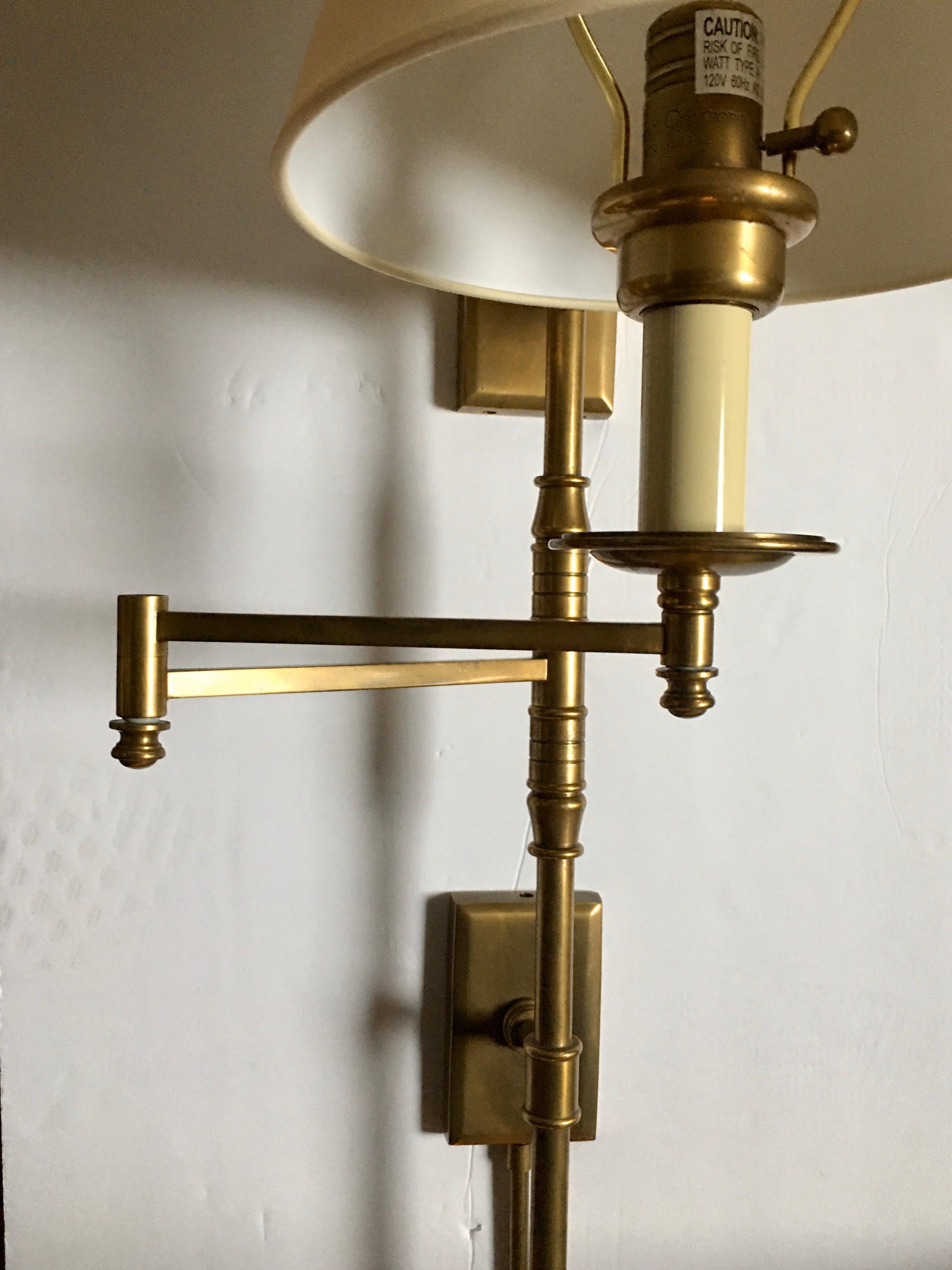Aged brass swing arm wall sconce by Chapman & Meyers for Visual Comfort Lighting. The dorchester task sconce has a double back plate with a plugin cord. Light fixture can also be hardwired. New natural paper shade included. Lamp shade still wrapped