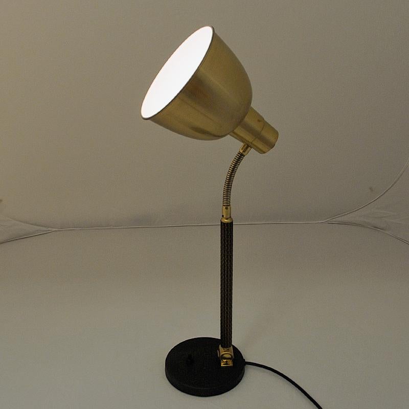 Classic Norwegian brass and metal tablelamp by Selecto AS in the 1950s. Brass shade and body with a black painted metal base. Light switch located on the base. Brass shade and body adjustable back and forth. Stem with a rattan lock. Marked with