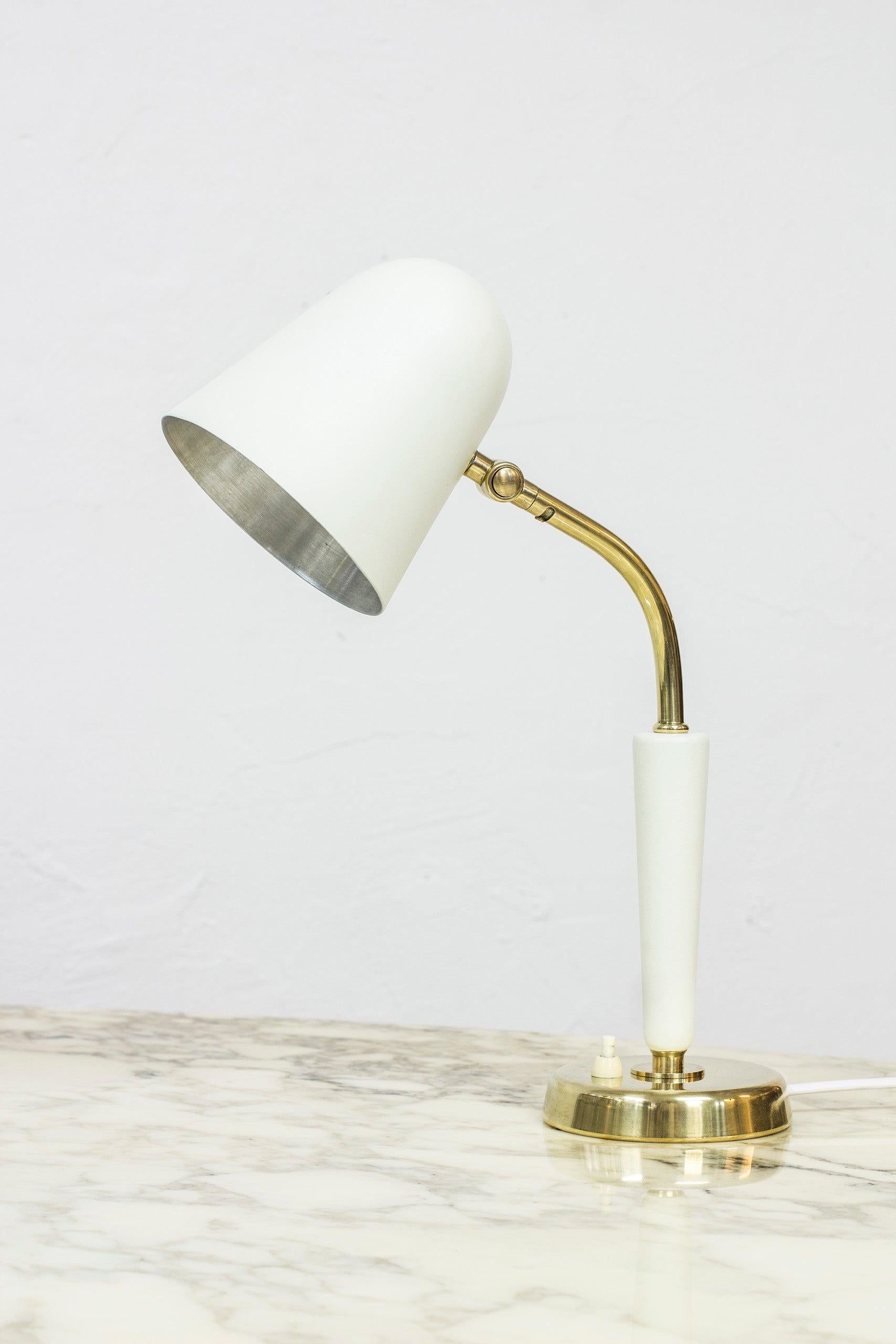 Table lamp designed by Bertil Brisborg. Produced by Nordiska Kompaniet in Sweden during the 1950s. Made from polished brass, wood and aluminum shade in creme white. Light switch on the base in working order. Adjustable in angle and to the sides.