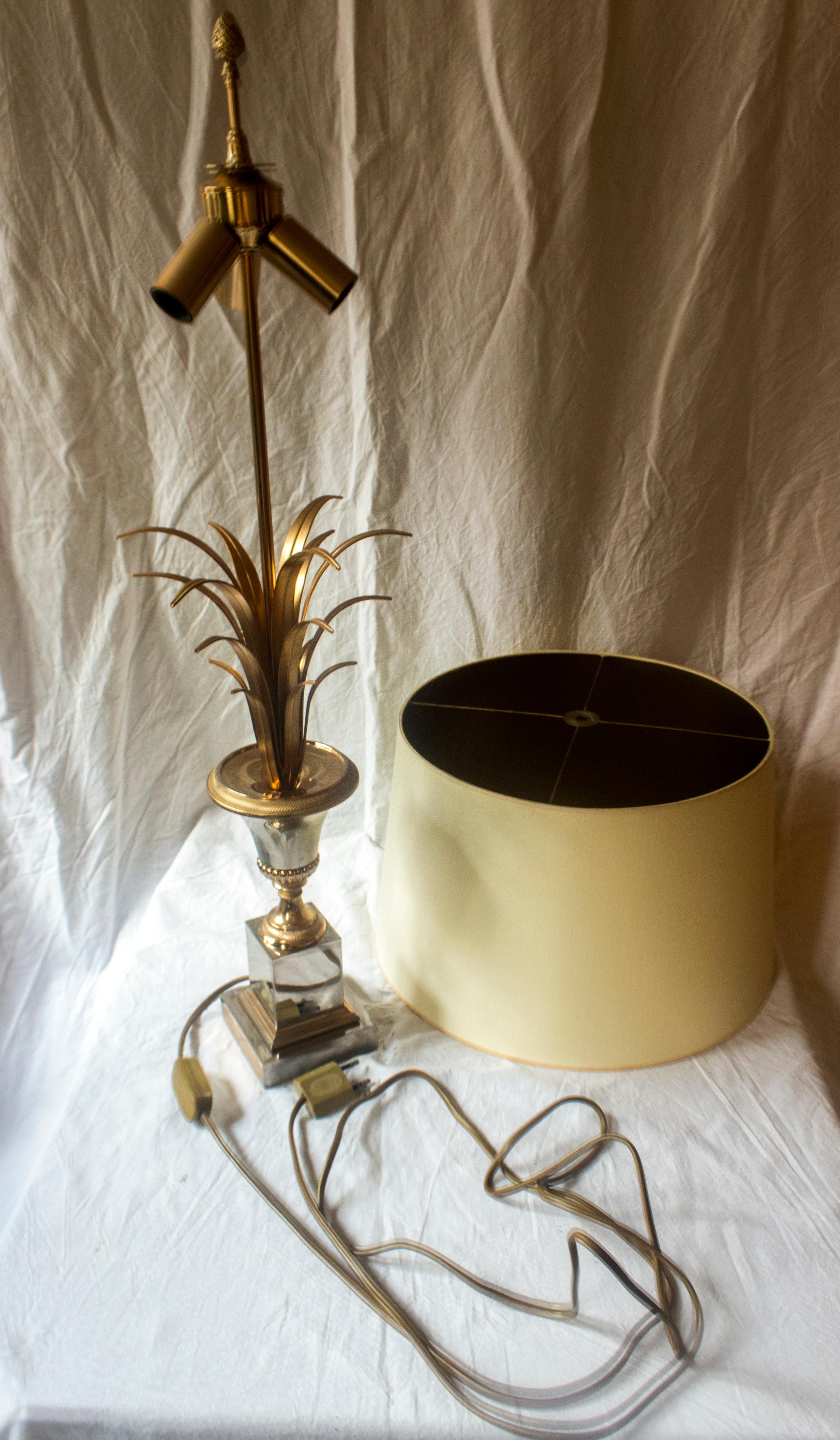 This magnificent Hollywood Regency style Boulanger table lamp, reminiscent of Maison Charles, is crafted from gilded metal and features an original lampshade adorned with pineapple leaves. This authentic vintage table lamp is from Belgium and dates