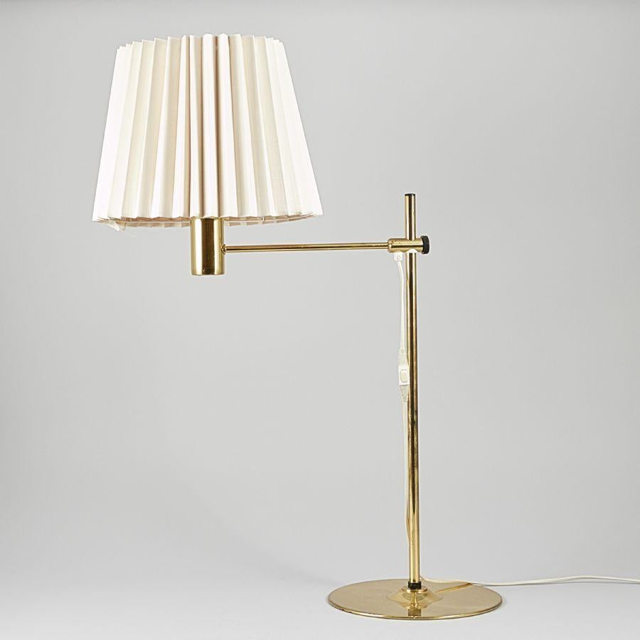 Lampe de table raffinée du milieu du siècle, conçue par Hans-Agne Agnes dans les années 1960, fabriquée en Suède. Cette pièce élégante est dotée d'un cadre en laiton poli et d'un bras horizontal réglable, permettant un éclairage flexible. Elle