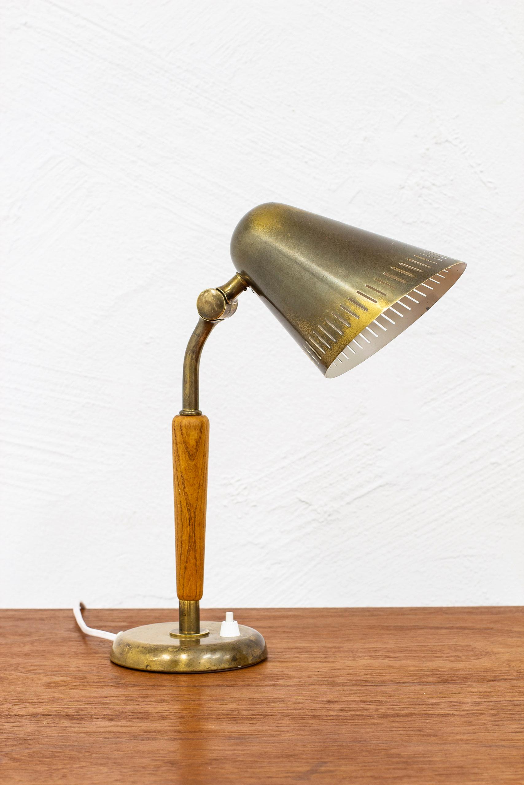 Table lamp model number 15365 designed by Harald Elof Notini. Produced in Stockholm by Böhlmarks lampfabrik during the 1940-50s. Made from brass and elm. Adjustable in angle. With light switch on the bas in working order. Good vintage condition with