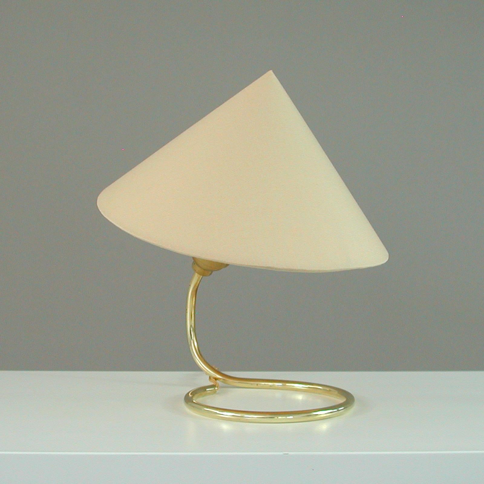 This mid-century table lamp was designed and manufactured in Austria in the 1950s by JT Kalmar.

The light features a brass base and a witch hat shaped lampshade. An awesome period style design with the shade on top of a wire frame which is