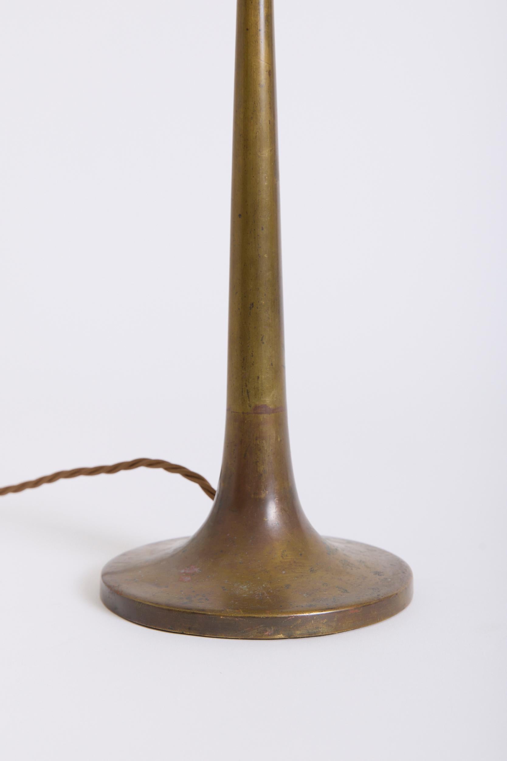 A brass table lamp 
France, mid 20th Century
With the shade: 52 cm high by 31 cm diameter
Lamp base only: 37 cm high by 13.5 cm diameter