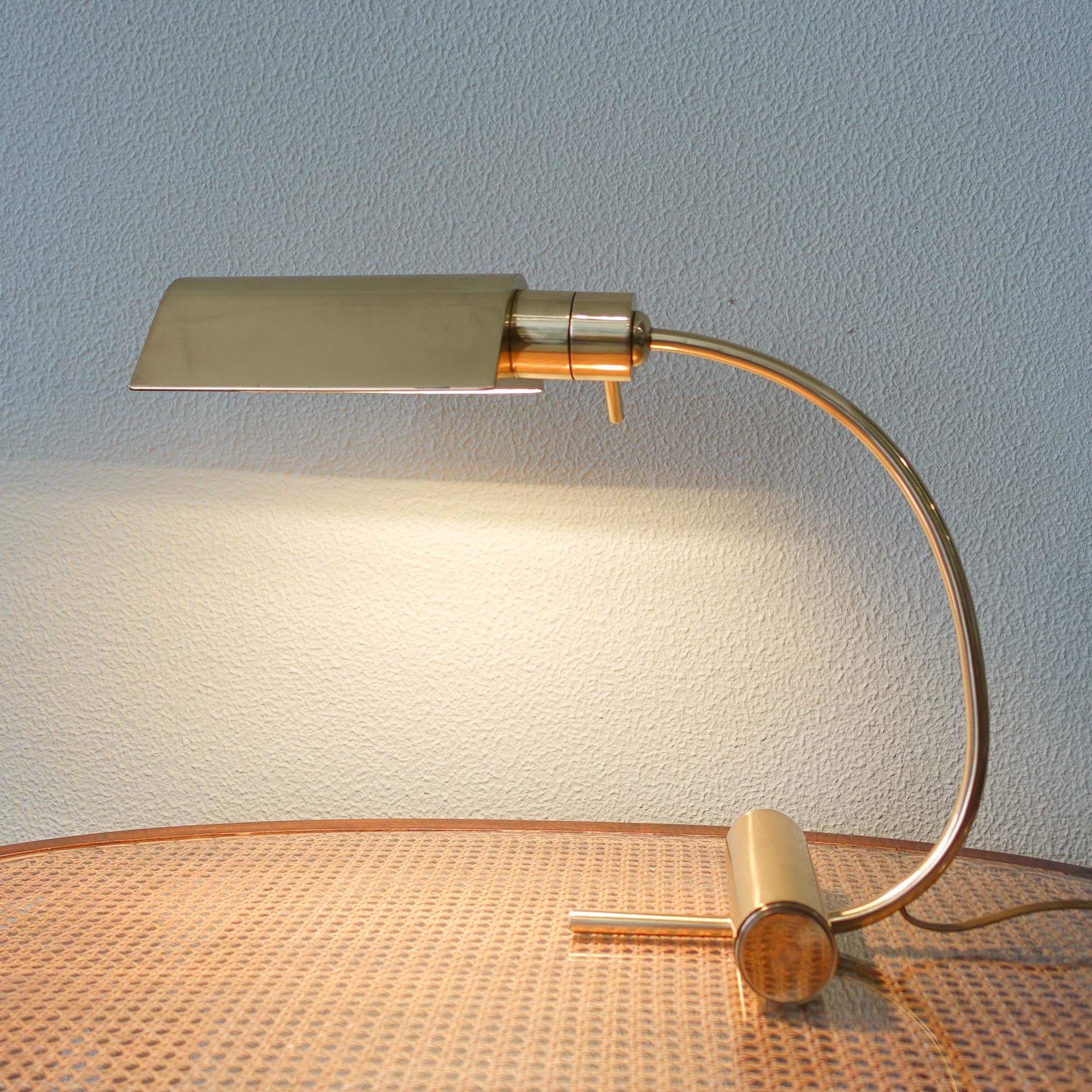This table lamp was designed and produced by Boulanger in Belgium, during the 1960's. It features a brass cylindrical tubular base were a curved brass rod arm is attached. Finishes with a triangular prism lampshade with some holes that allows the