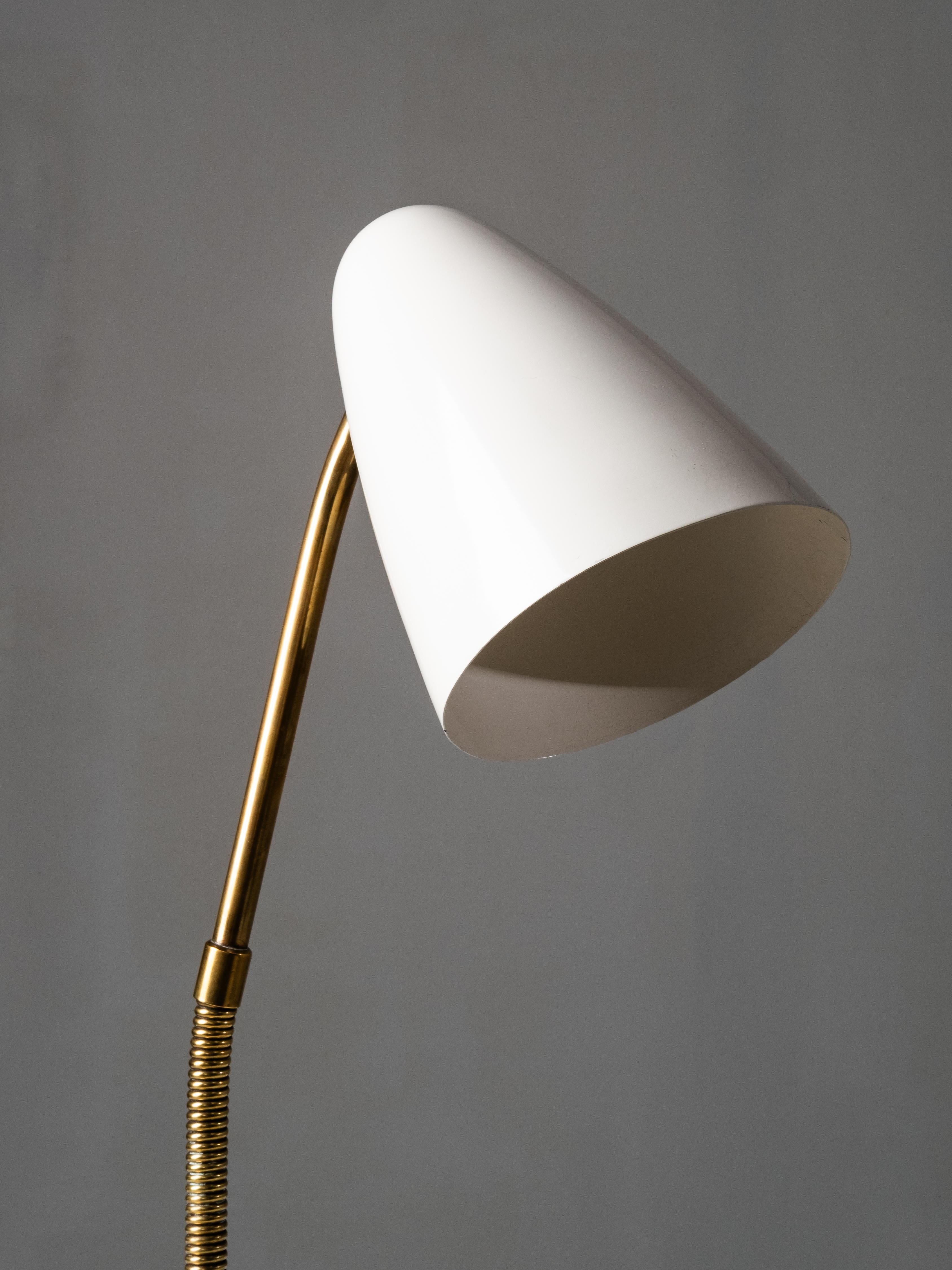 Esta lámpara de sobremesa Modelo 40-068 fue diseñada por Lisa Johansson-Pape y fabricada por Orno en la década de 1950. La lámpara tiene una base abovedada de latón con un cuello enrollado de latón y un vástago angulado de latón que conduce a una