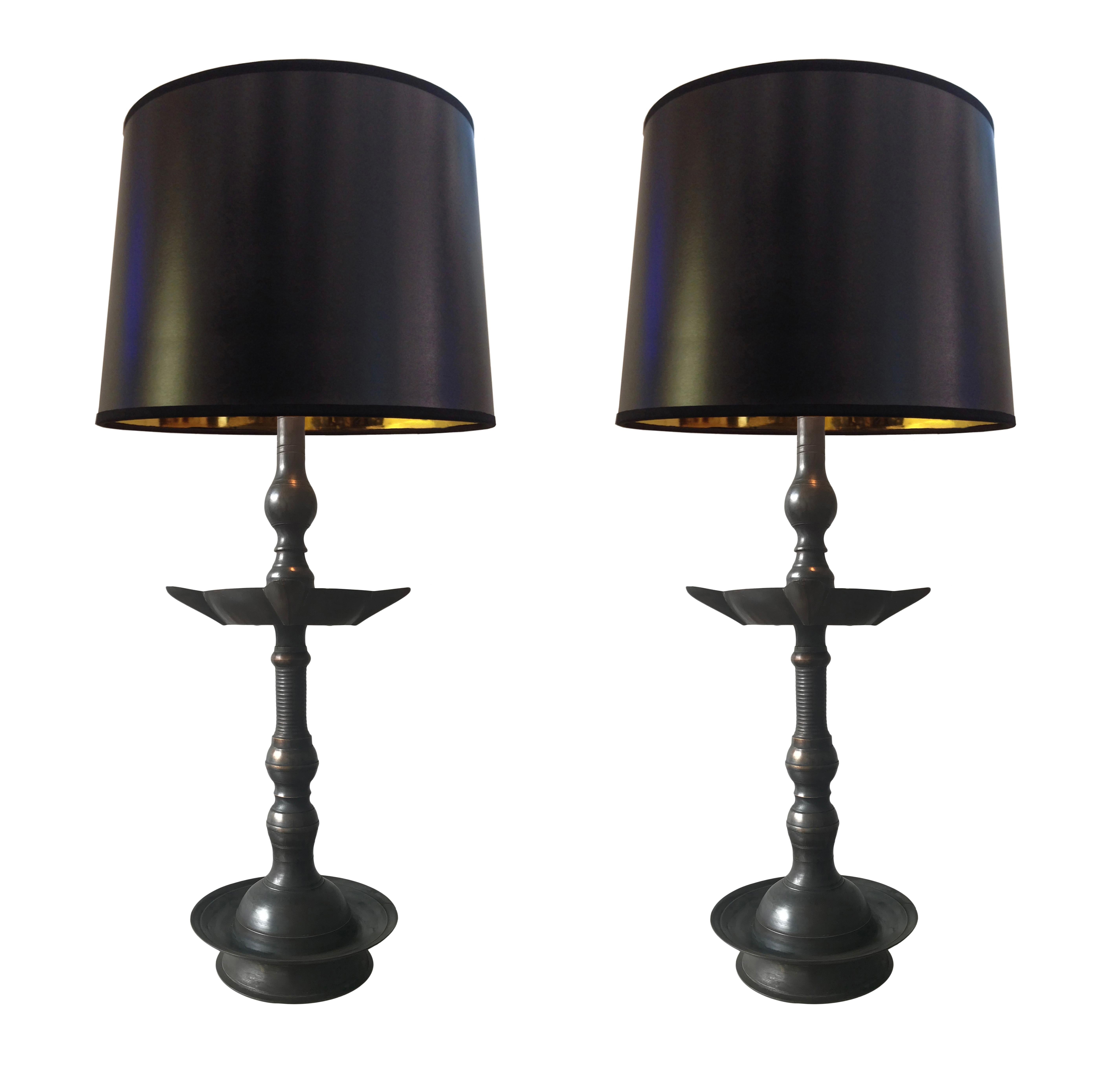 Two heavy brass Indian oil lamps. Electrified with switched E26 lightbulb holders and either, Euro-style shade-ring or harp fitting. 
The brass has been extensively aged over a period of time to produce the rich, dark finish with brassy highlights.