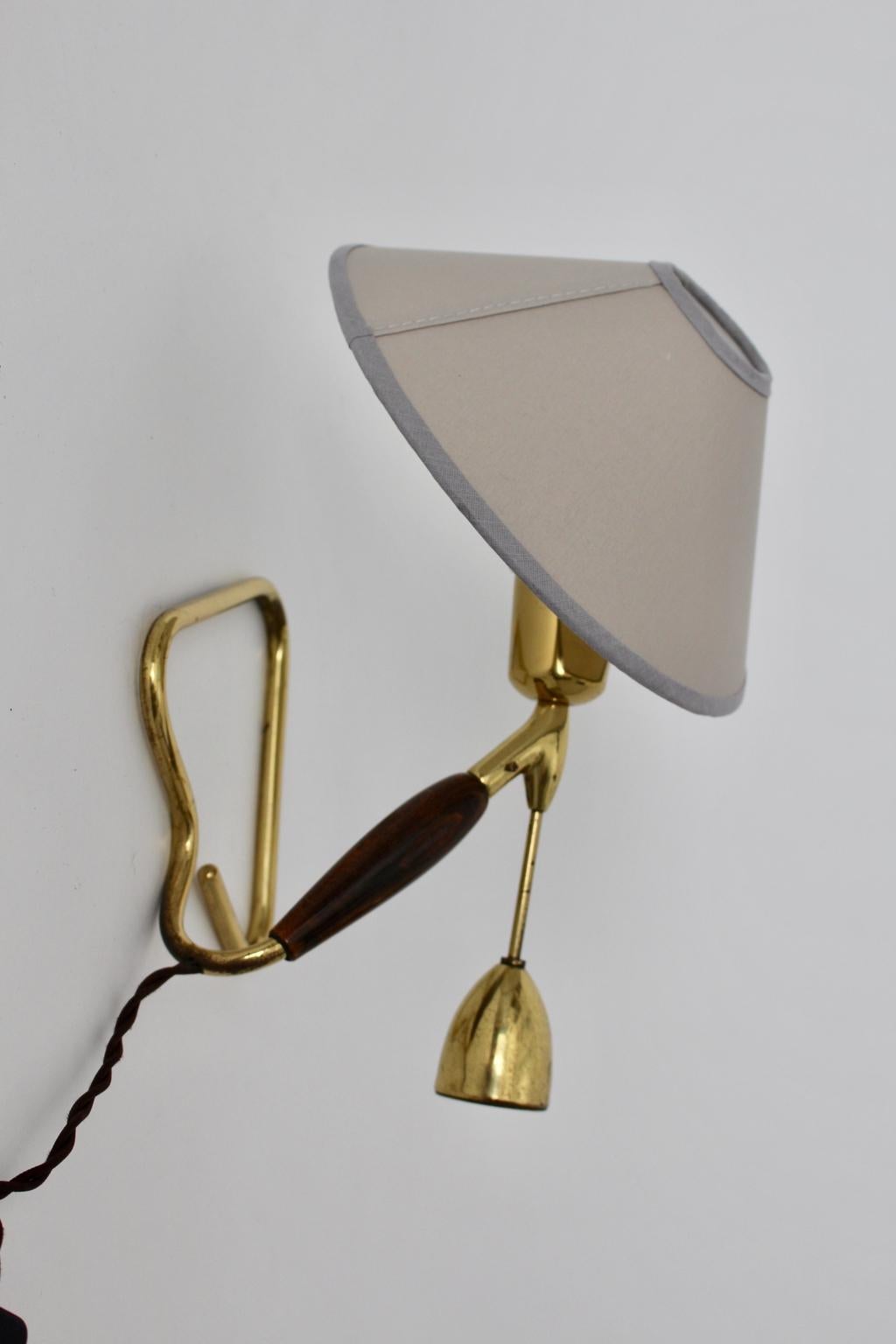 This extraordinary lighting is an adjustable brass table lamp or a wall lamp.
The lamp by Rupert Nikoll, 1950s Vienna features a beechwood handle and a counterweight. 
The counterweight is for moving the direction of the shade.
The lampshade is