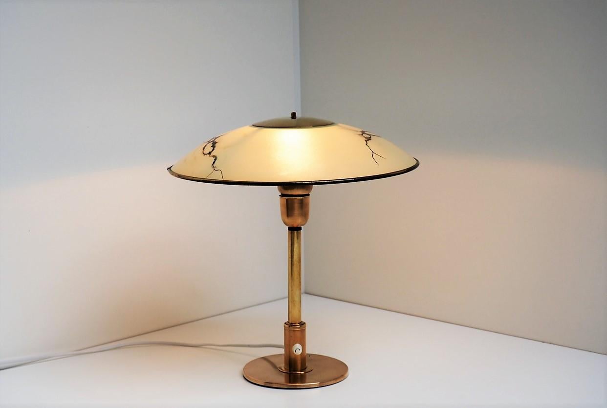 Rare table lamp made in brass together with a yellow glass shade decorated with brown and green abstract pattern, and the shade is lined with brass. 

The light is a Danish design from the 1930s-1940s and can very well be made by eighter Fog &