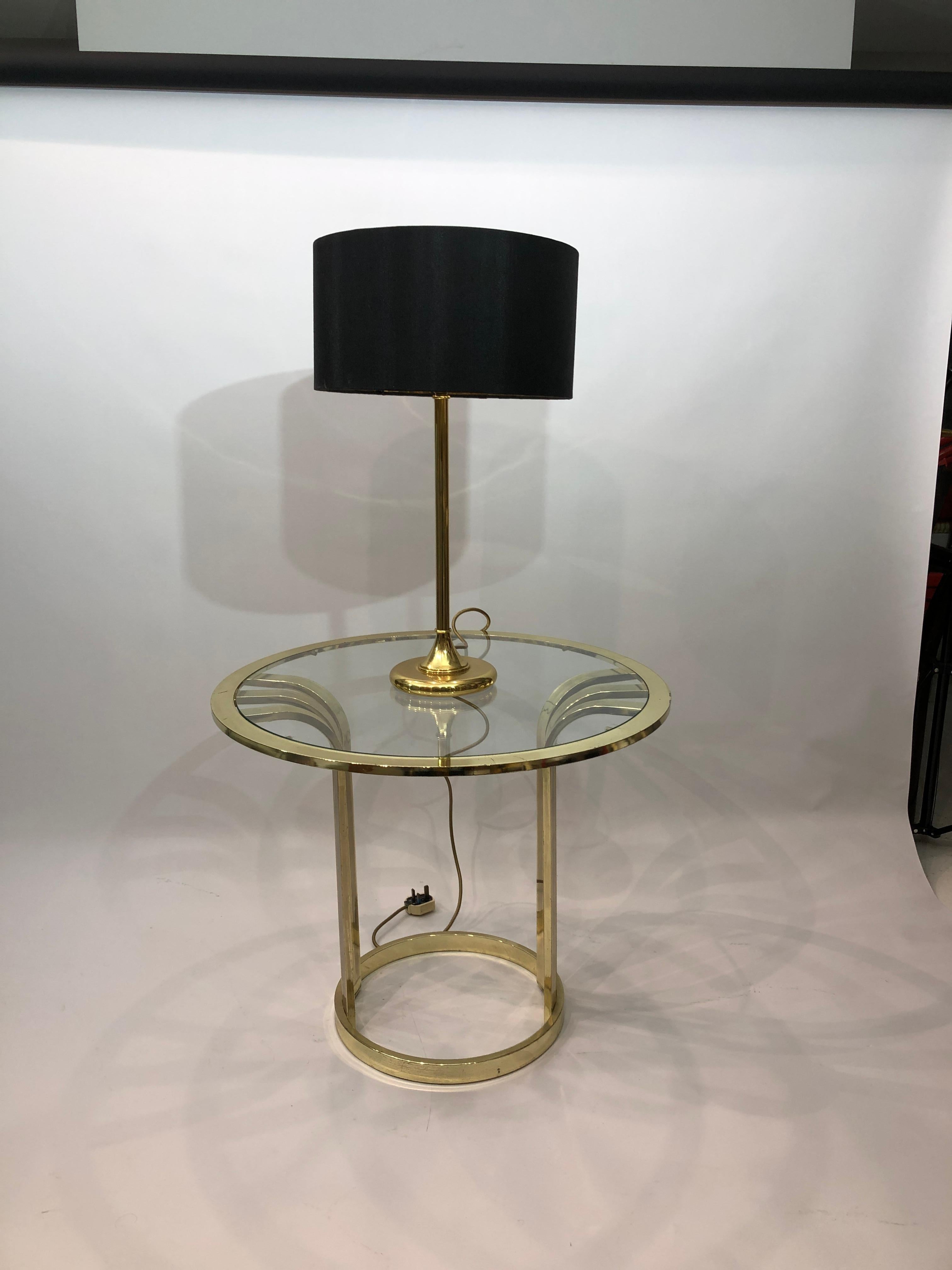 Une lampe de table minimaliste à tige en laiton ou à base ronde et un abat-jour noir. L'abat-jour est une édition ultérieure et n'est pas l'original, mais nous pensons qu'il convient parfaitement. Si vous n'aimez pas l'abat-jour, nous pouvons vous