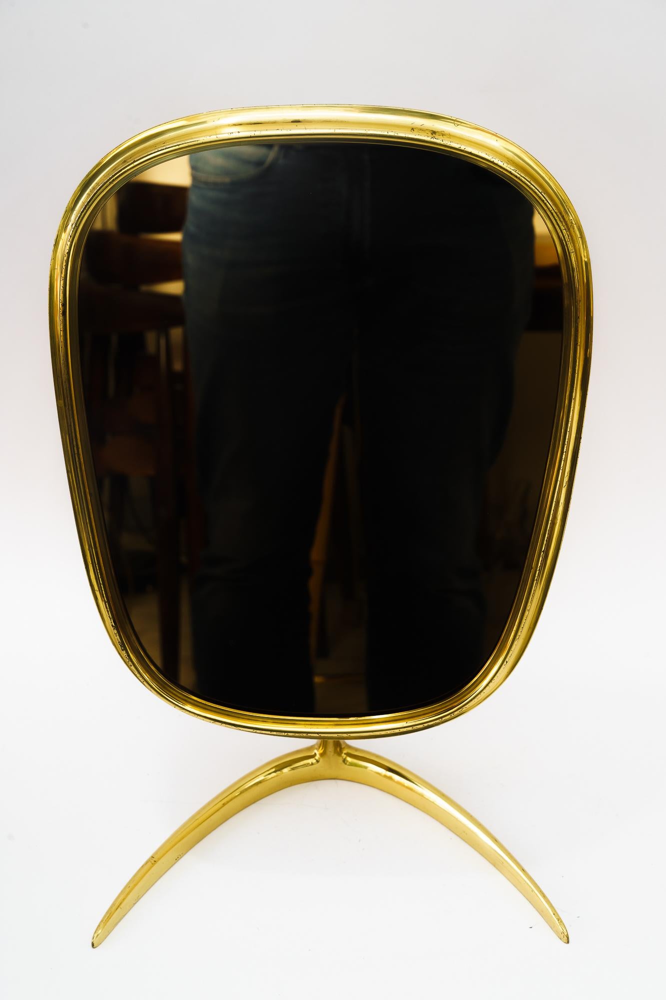 This original midcentury table mirror was produced in the 1950s in Germany by the Vereinigte Werkstätten München. 
Brass metal base and brass mirror glass frame at the top. 
Minimalistic design of the 1950s. 
Original condition