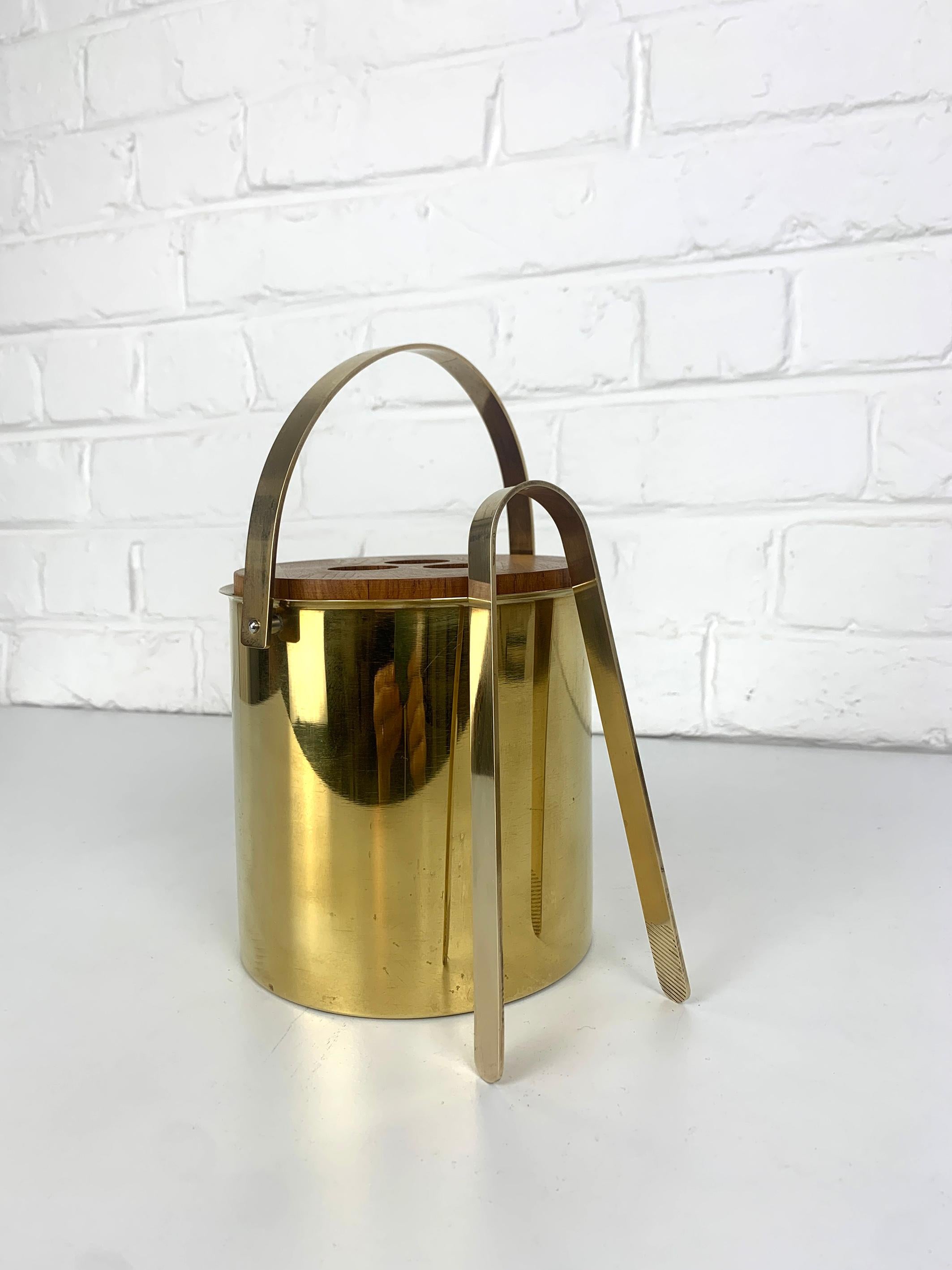 Beautiful set of ice bucket and ice tong in brass with a lid in solid teak wood. Iconic creation by Danish designer Arne Jacobsen for Stelton Brassware. 

The brassware line was only produced is sought after today by collectors. It was only in
