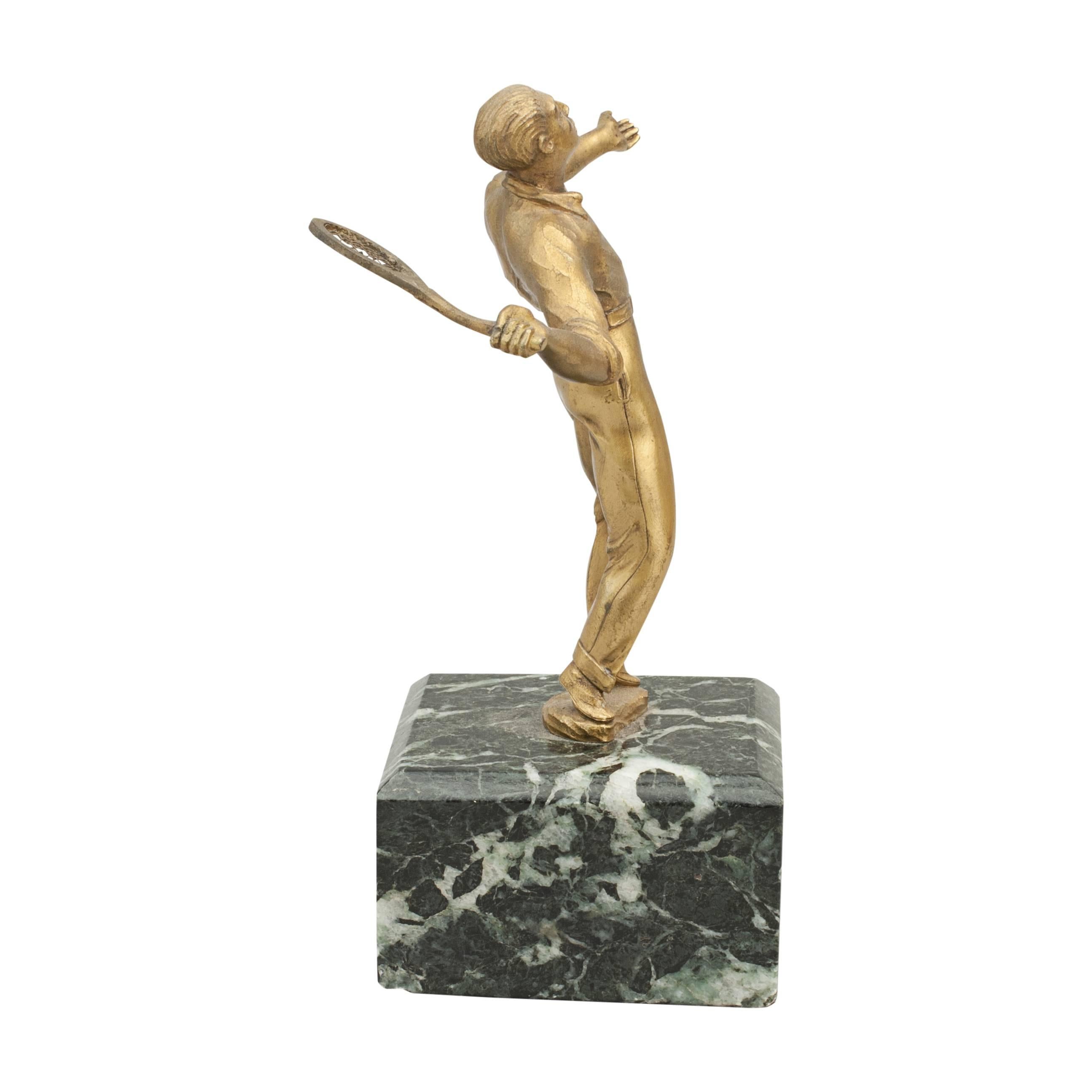 Antique tennis figure.
A fine figure of a male tennis player in serving position, dressed in long trousers and short sleeved shirt. The figure is made in brass, finished in gold color and stands on a marble base 2' tall.