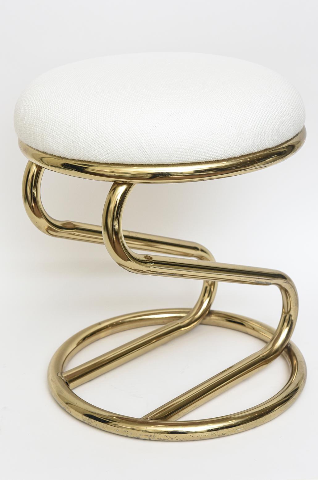 This vintage zig zag stool is brass toned in color over steel. It is not brass. It has not been re-plated in brass either. The seat has been re-upholstered in a white textural cotton. Could be used as a footstool or a small stool in a bathroom or