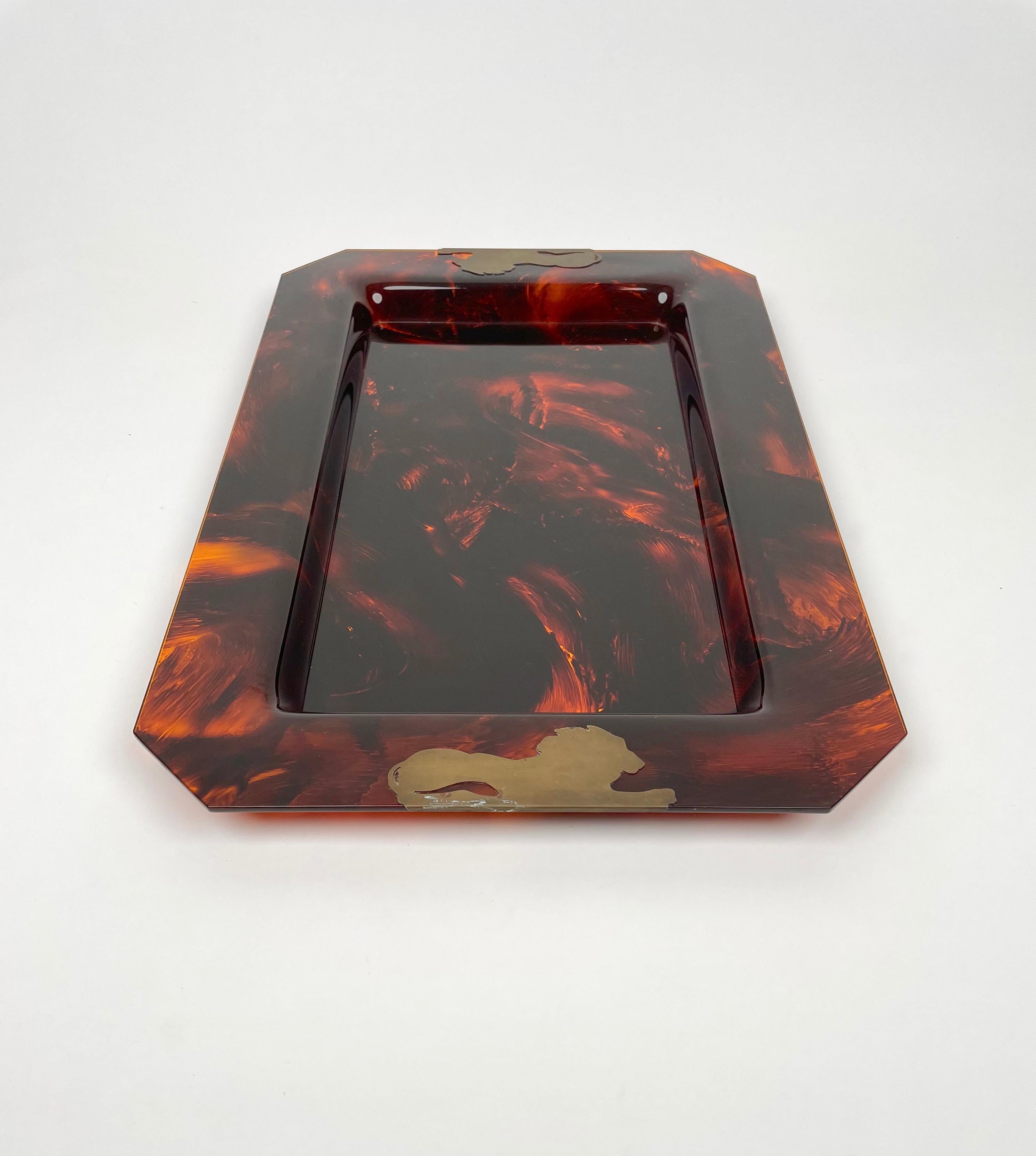 Rectangular centerpiece serving tray in tortoise-shell-effect lucite featuring two brass lions on two sides. 

Made in Italy in the 1970s.