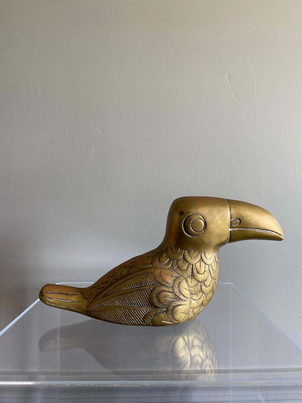 Beautiful brass toucan sculpture. This piece is both whimsy and a signature of Mid Century décor. The piece has incredible detail: striking lines and arches that delineate the figure along with an enchanting expression that brings a pleasing