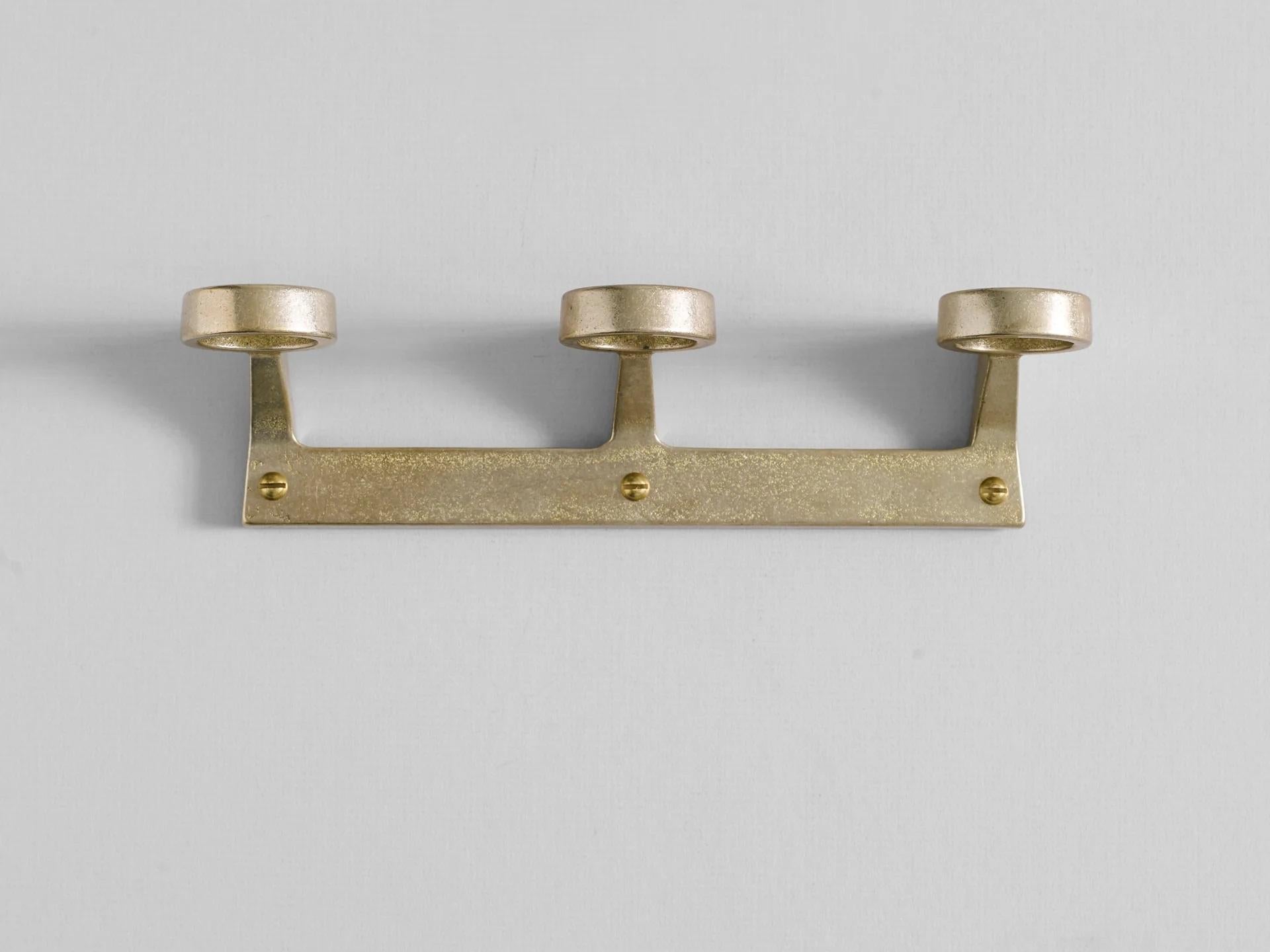 Brass Trio Bottle Bracket by Henry Wilson
Dimensions: W 23.5 x D 7.1 x H 5.7 cm
Materials: Brass.

Available in Solo, Duo, or Trio versions.

Available in three configurations, the Bottle Bracket is designed to accommodate one, two, or three