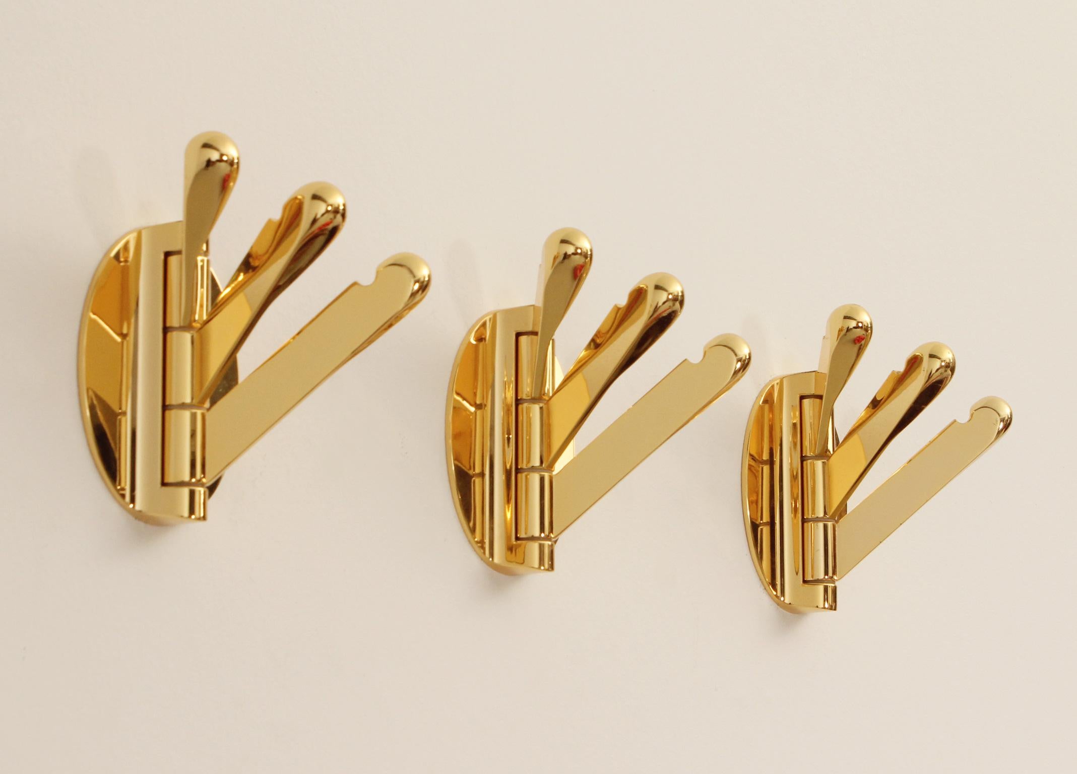 Brass triple folding wall coat racks, Spain, 1970's. Composed of three movable hangers each that can be moved according to use. 