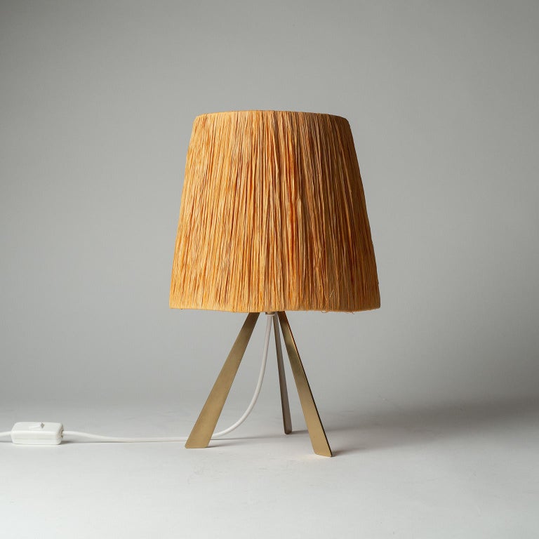 Charming table lamp from the 1960s. Brushed brass tripod base with a raffia shade. The raffia has an orange tint which has partially faded over the years. One original brass E27 socket with new wiring.