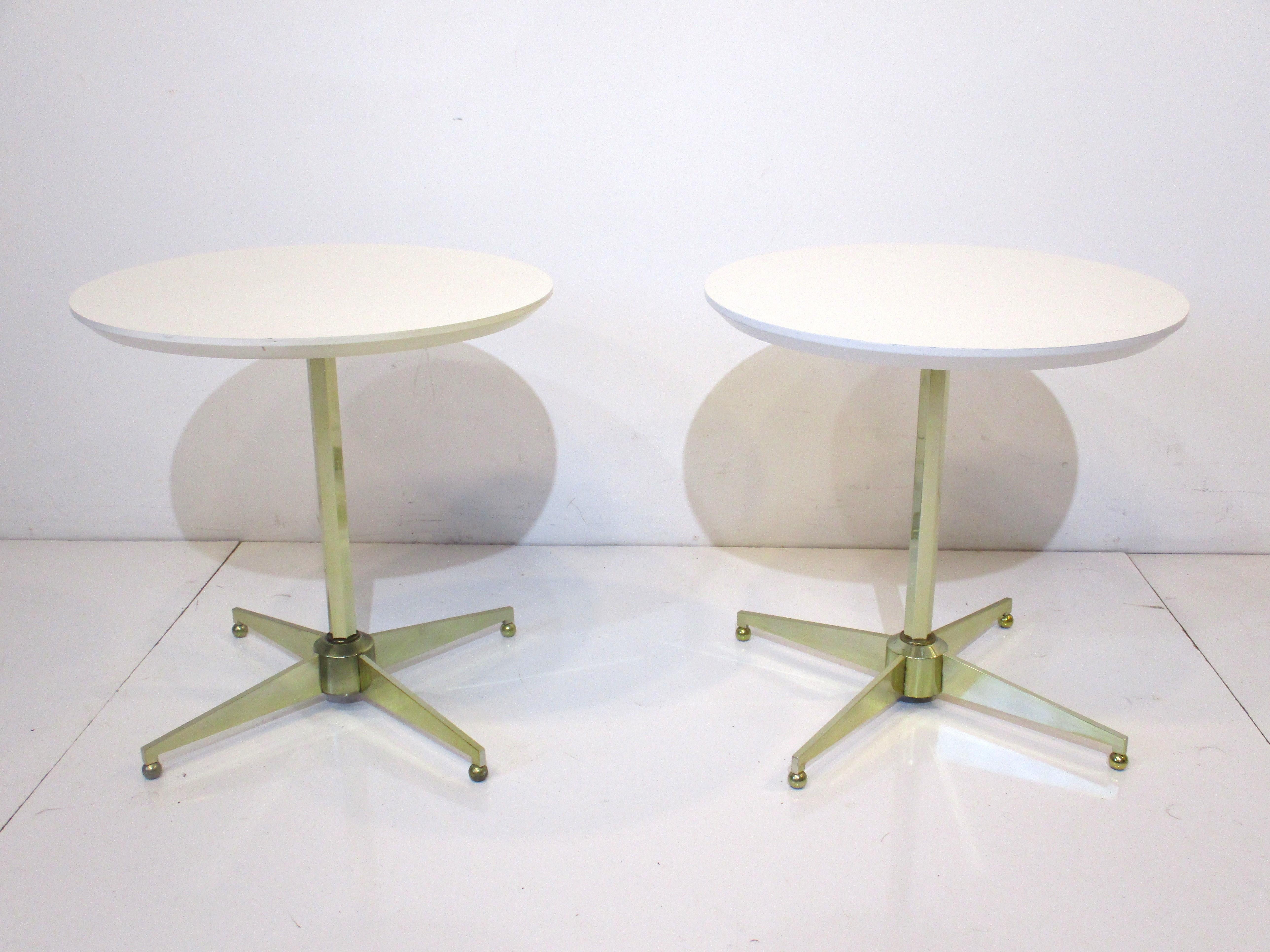 A pair of star based side tables with white wood and laminate round tops having nice tailored octagon shaft and base with ball feet all in brass . A great look that would work with many different styles and interiors manufactured by the American of