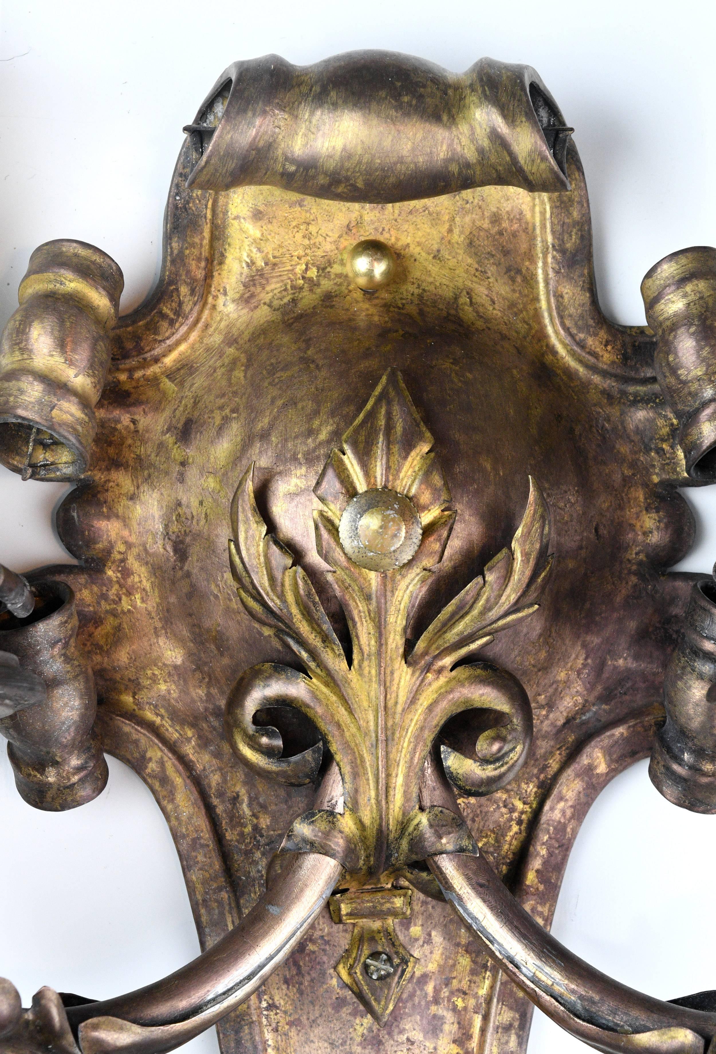 This gorgeous brass two candle Rococo sconce is laden with ribbon-like curls throughout. The curving, unfurling lines give the fixture a natural, organic feel, and the richly patina-ed brass adds to the old world charm. If you are looking for an