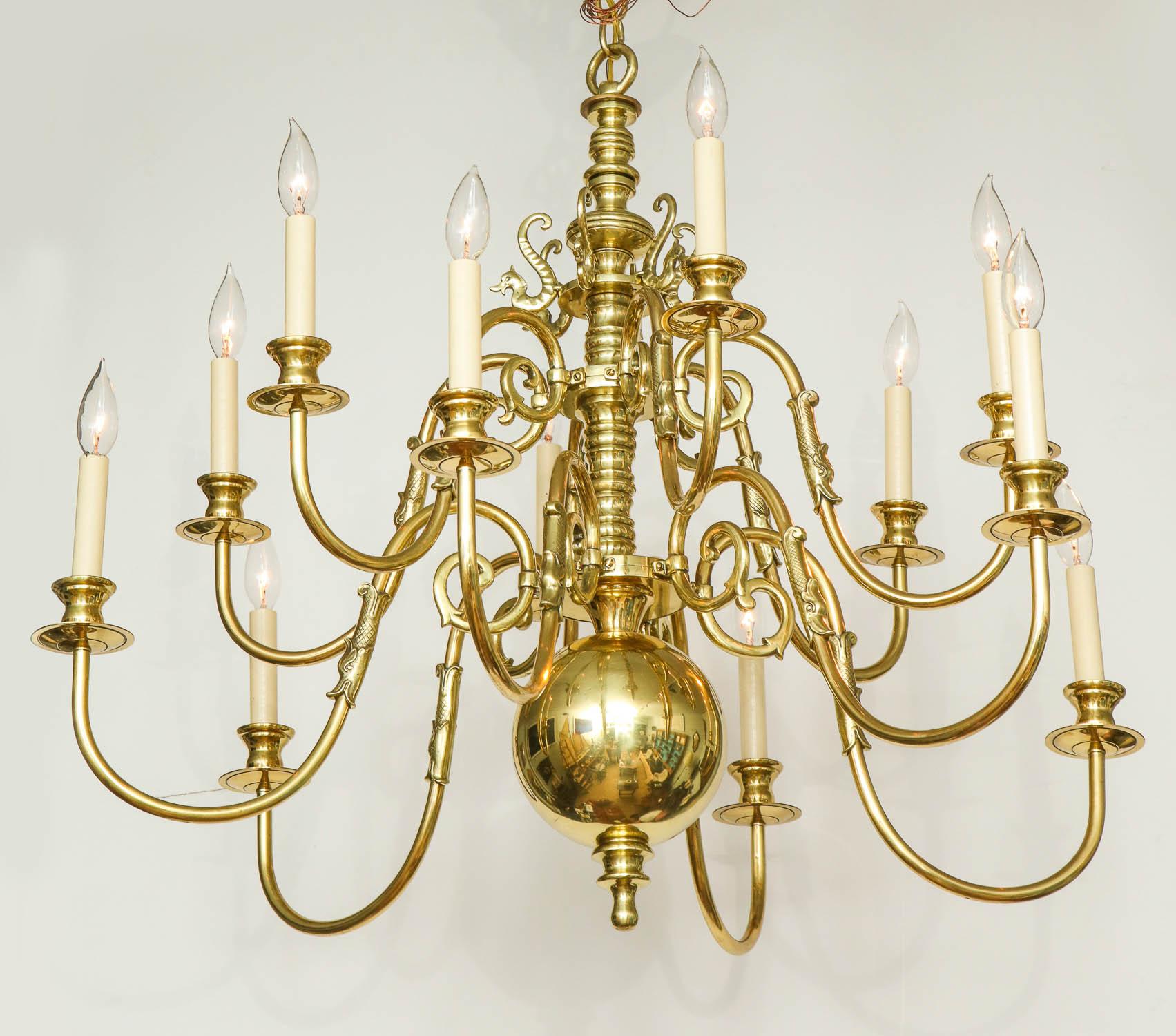 Fine Baroque style brass 12-light two-tier chandelier having balustrade turned shaft, the scrolled arms with dolphin spouts and overscale ball finial.