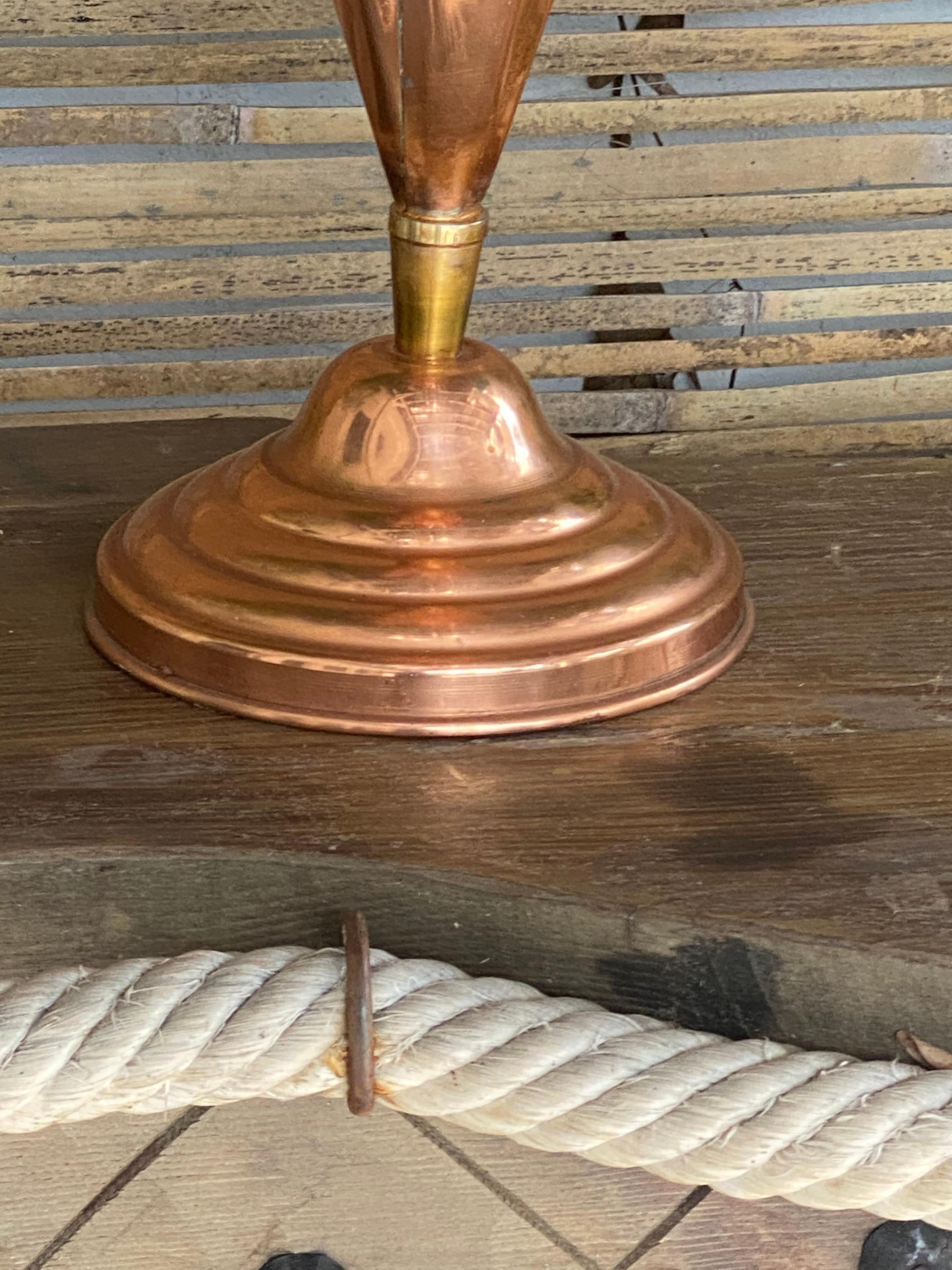 This umbrella stand is in brass and cooper. It has been made in Italy in the 1960s.
The rod and the base are in brass, and the casing is in copper.
The rod is finished at the top by a brass handle, and the shape of the object is an umbrella.
  