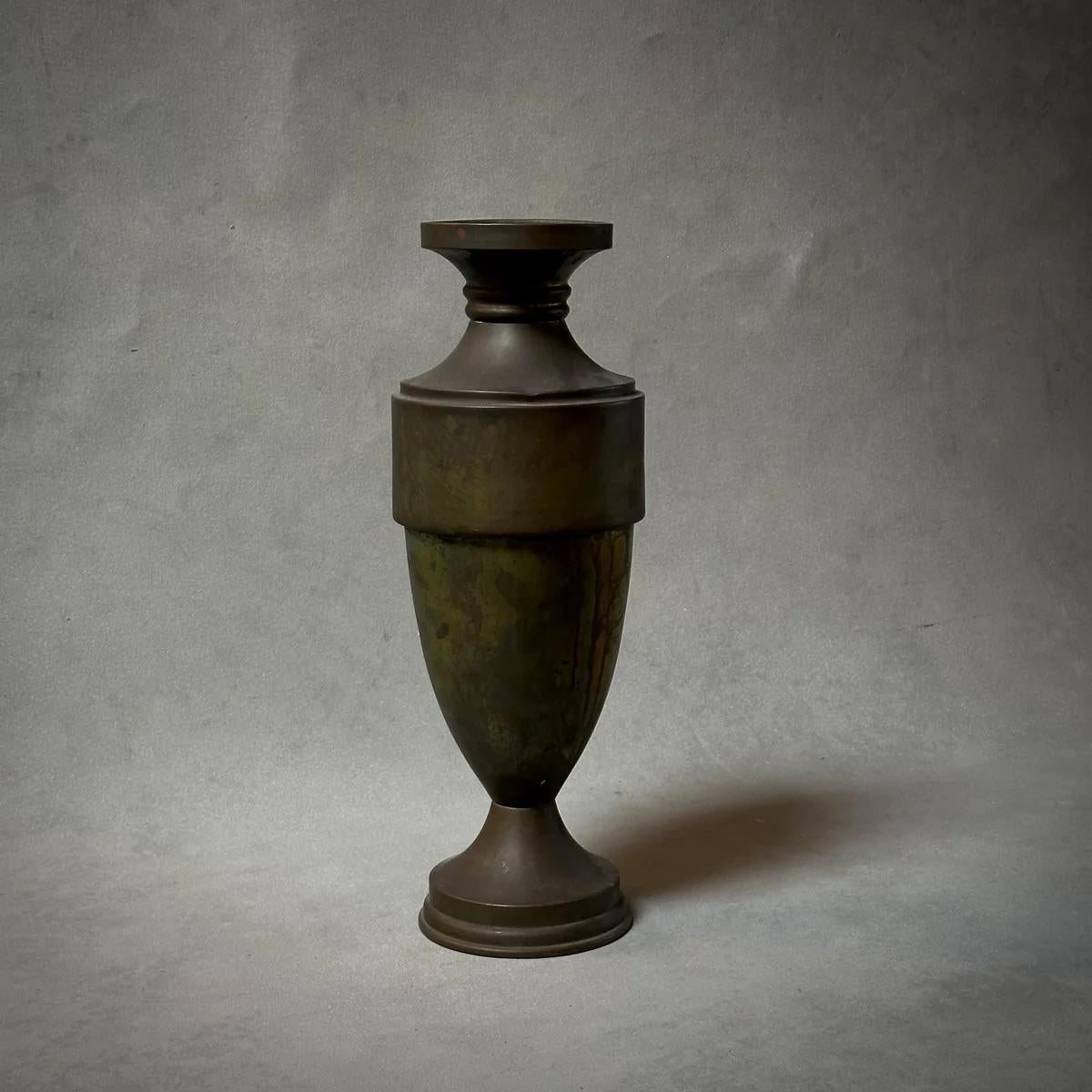 Questo vaso a forma di urna in ottone francese è caratterizzato da una patina color bronzo scuro e da una base ponderata, che presenta un mix di semplicità e imponenza. Le sue linee pulite e la sua forma elegante conferiscono una bellezza dignitosa