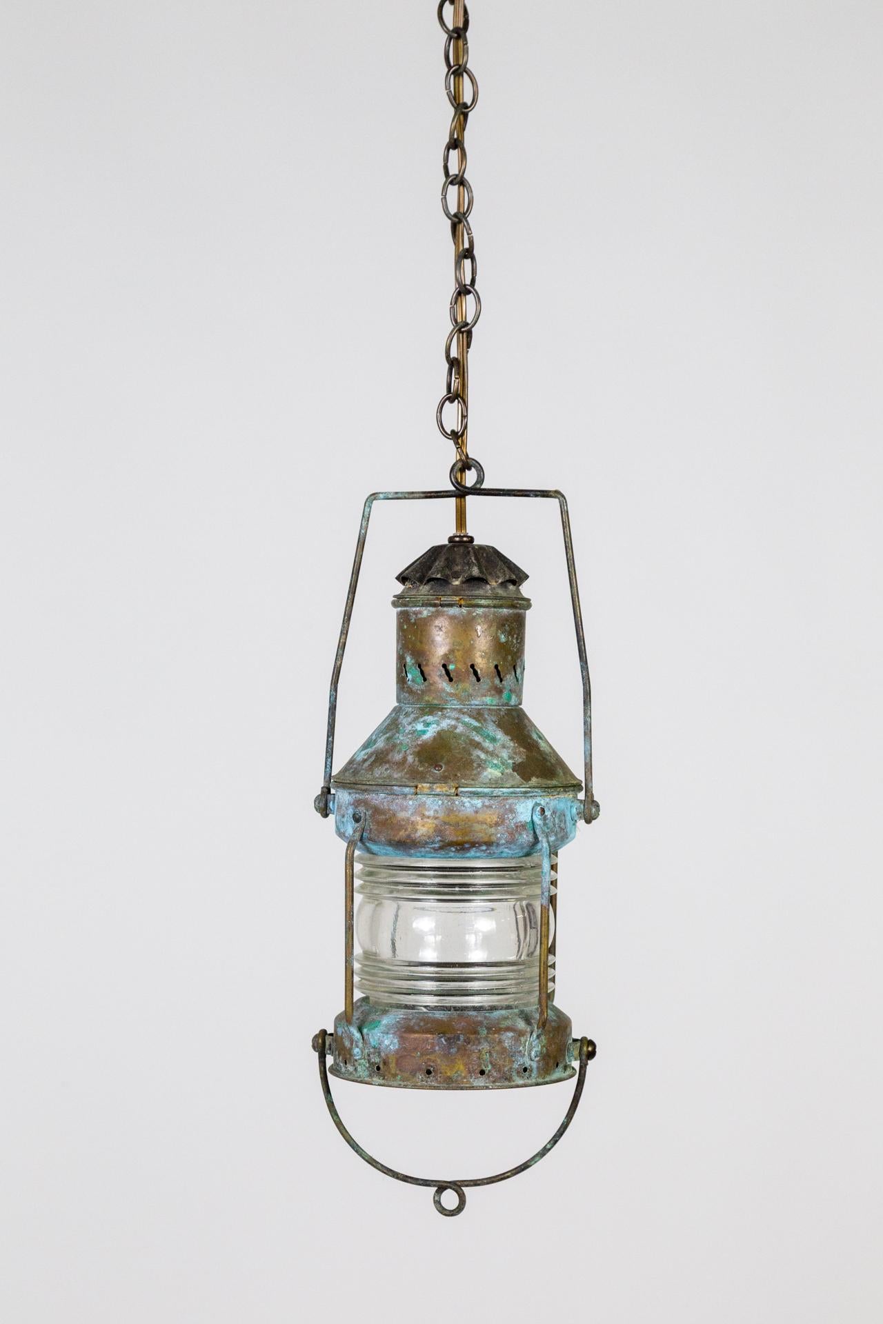 Lanterne suspendue du début du 20e siècle de forme cylindrique avec une belle diffusion du verre de Fresnel. Avec un remarquable laiton antique, bleu,  et patine vert-de-gris et une longue chaîne. Nouvellement câblé et transformé en lampe suspendue.