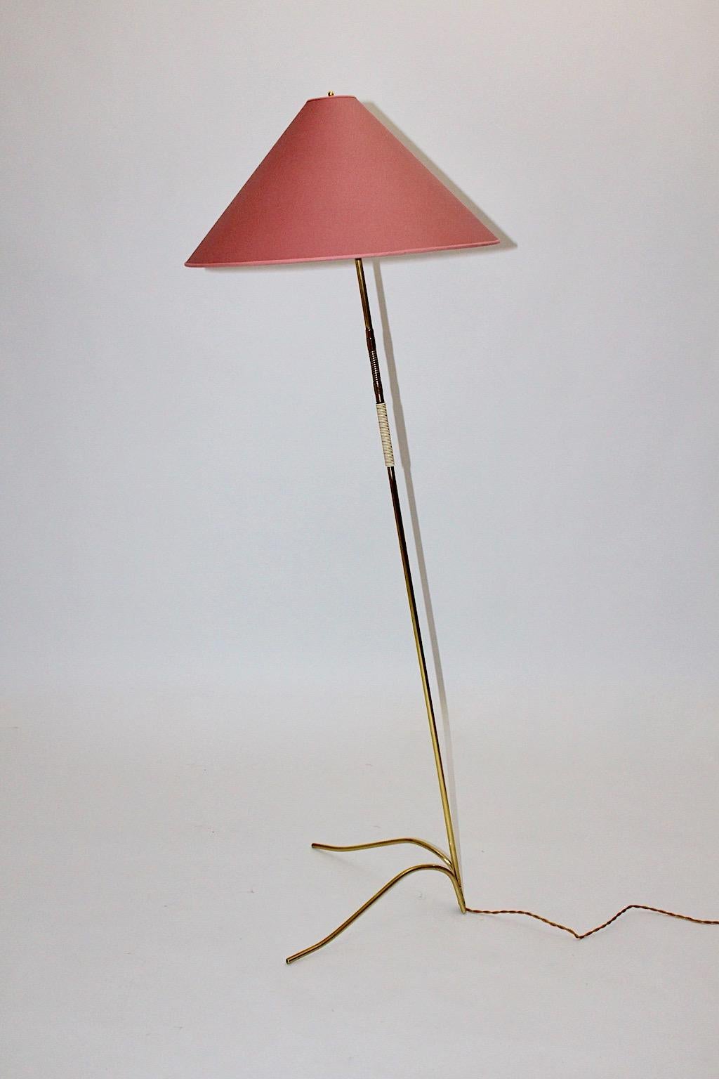 Brass vintage Mid-Century Modern floor lamp designed and manufactured by Rupert Nikoll, 1950, Austria.
This stunning floor lamp was made of polished brass tube with a plastic string handle and a renewed lamp shade, which shows a pastel tone in pink.