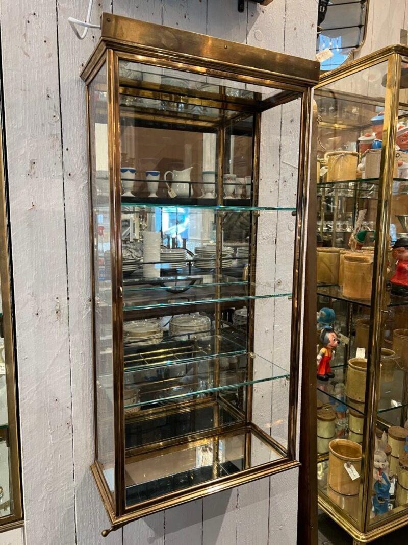 Elegante vetrina di SIEGEL-PARIS, degli anni '30 circa. Uno stile Art Deco bello e austero con profili semplici e forti.

La vetrinetta da parete è in ottone di qualità con 3 splendidi ripiani in vetro e mensole regolabili. La base e il pannello