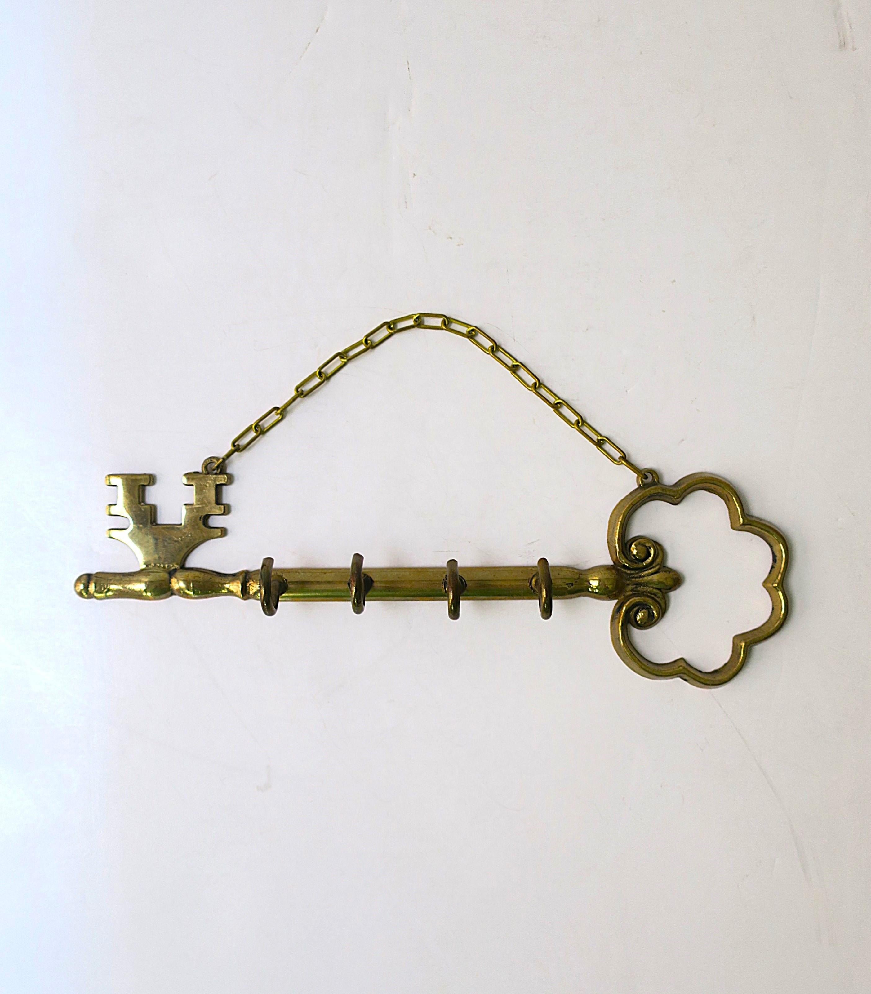 Portachiavi da parete in ottone, circa metà del XX secolo. Questo portachiavi da parete in ottone ha la forma di una chiave antica. Il pezzo ha quattro (4) ganci nella parte anteriore e una catena per appenderlo. Dimensioni: 8,63