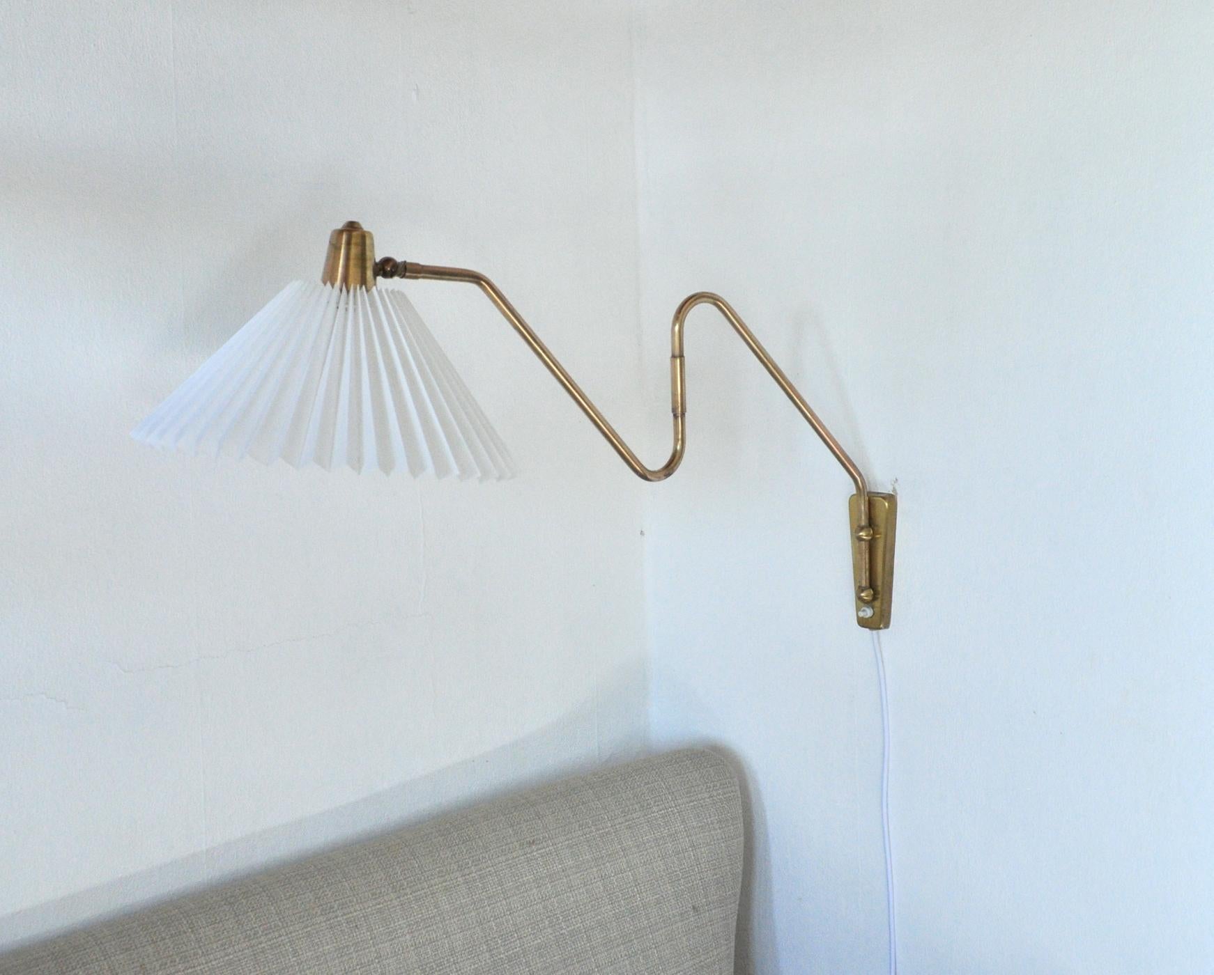 Brass wall lamp with two-piece swing arm.
Swivel and wall mount made in brass, mounted with a new pleated screen. 
Designed and produced in the 1950s by Norwegian Astra. 

Arm length incl. shade: 45 - 83 cm
Height: ca. 45 cm 
Shade: ca. 9/32.5 cm,