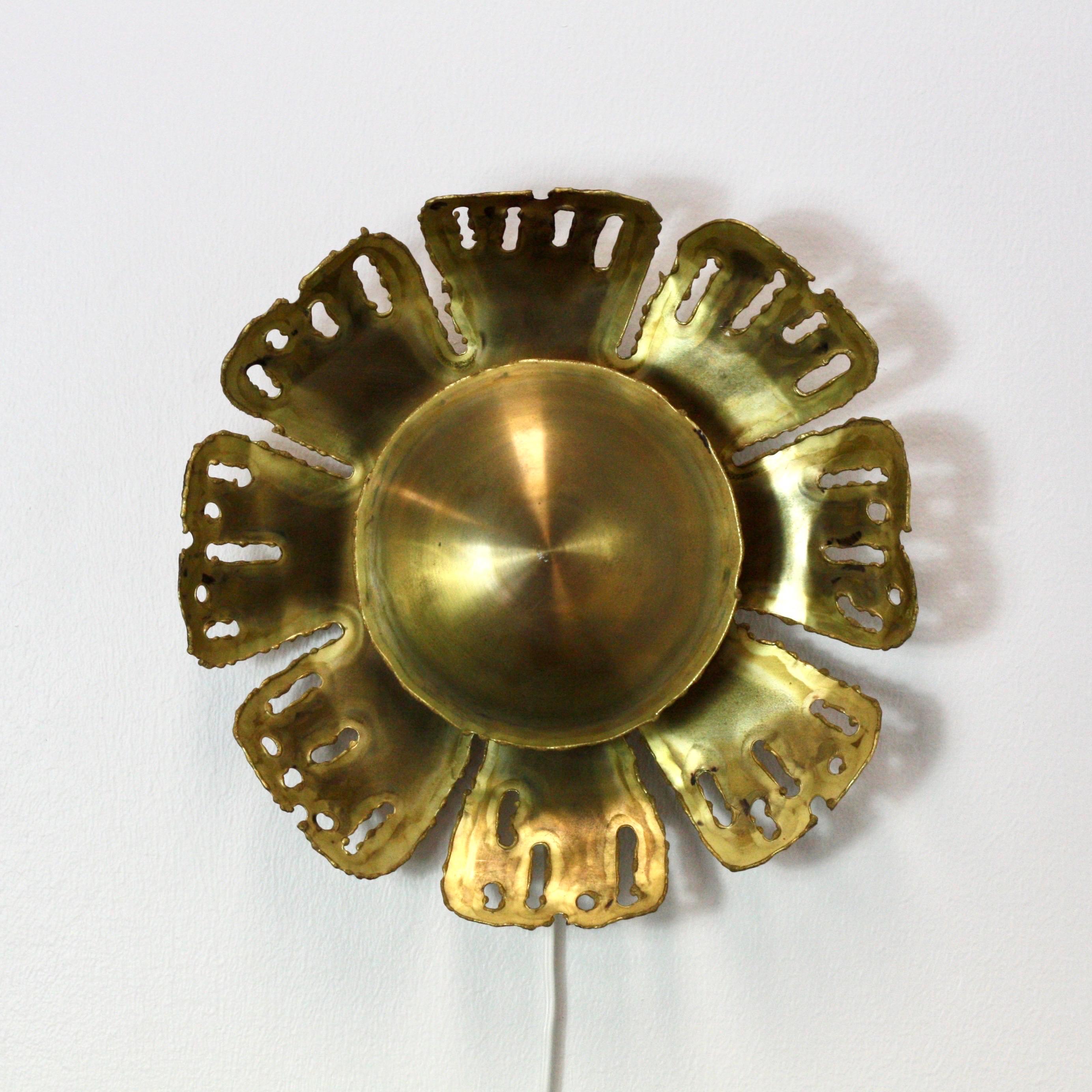A sun-shaped brass wall lamp designed by Svend Aage Holm Sørensen in the 1960s. This eye-catching design is a true masterpiece and trademark of the Danish designer. 

* A sunflower shaped brass wall sconce
* Designer: Svend Aage Holm Sørensen
*