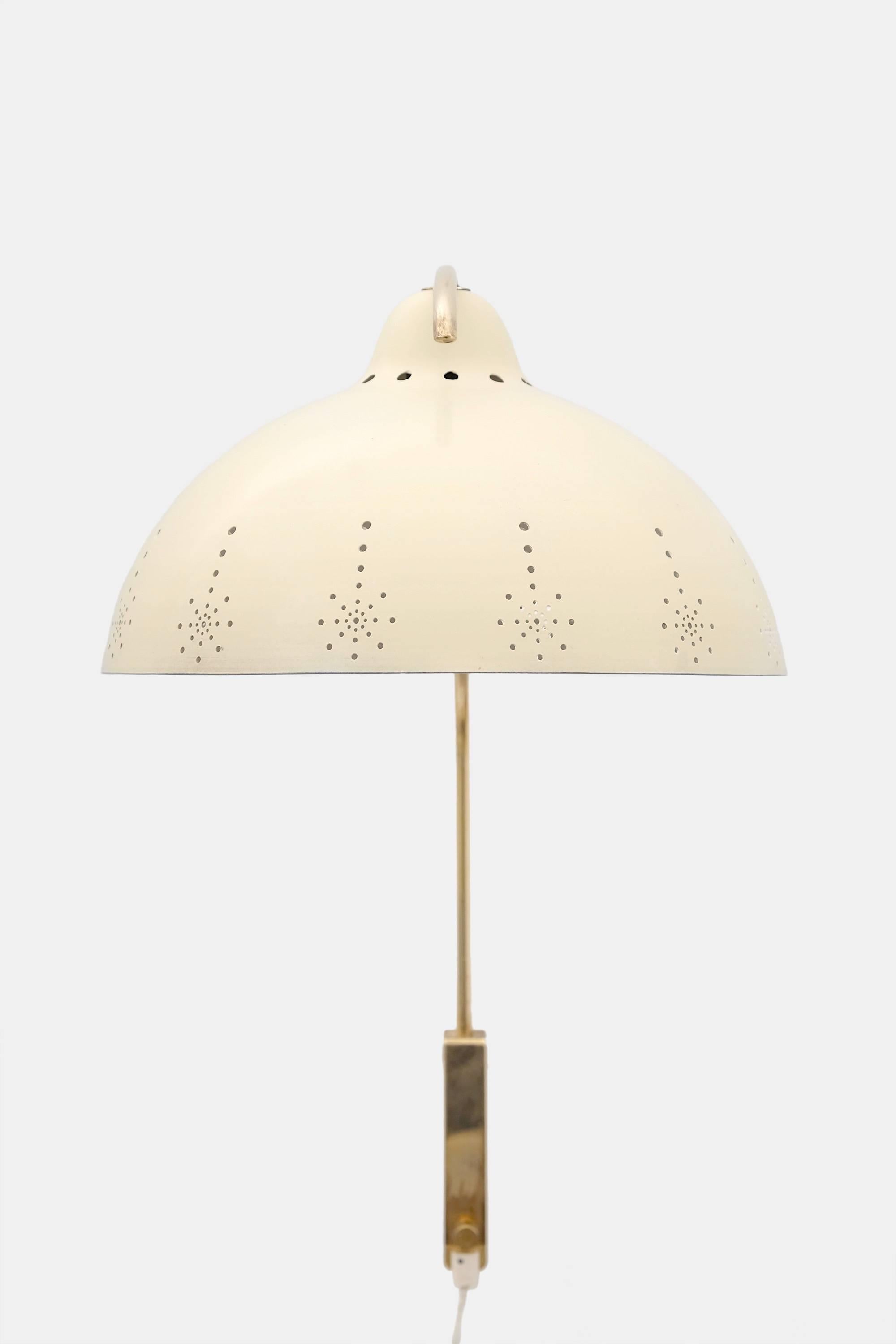 Elegant 1950s brass wall lamp by Valinte Oy, Finland. Brass stem and perforated aluminum shade which is painted cream color. Stem can be turned sideways and adjusted up and down. Light switch in the electric wire. Measure: Overall depth of the lamp