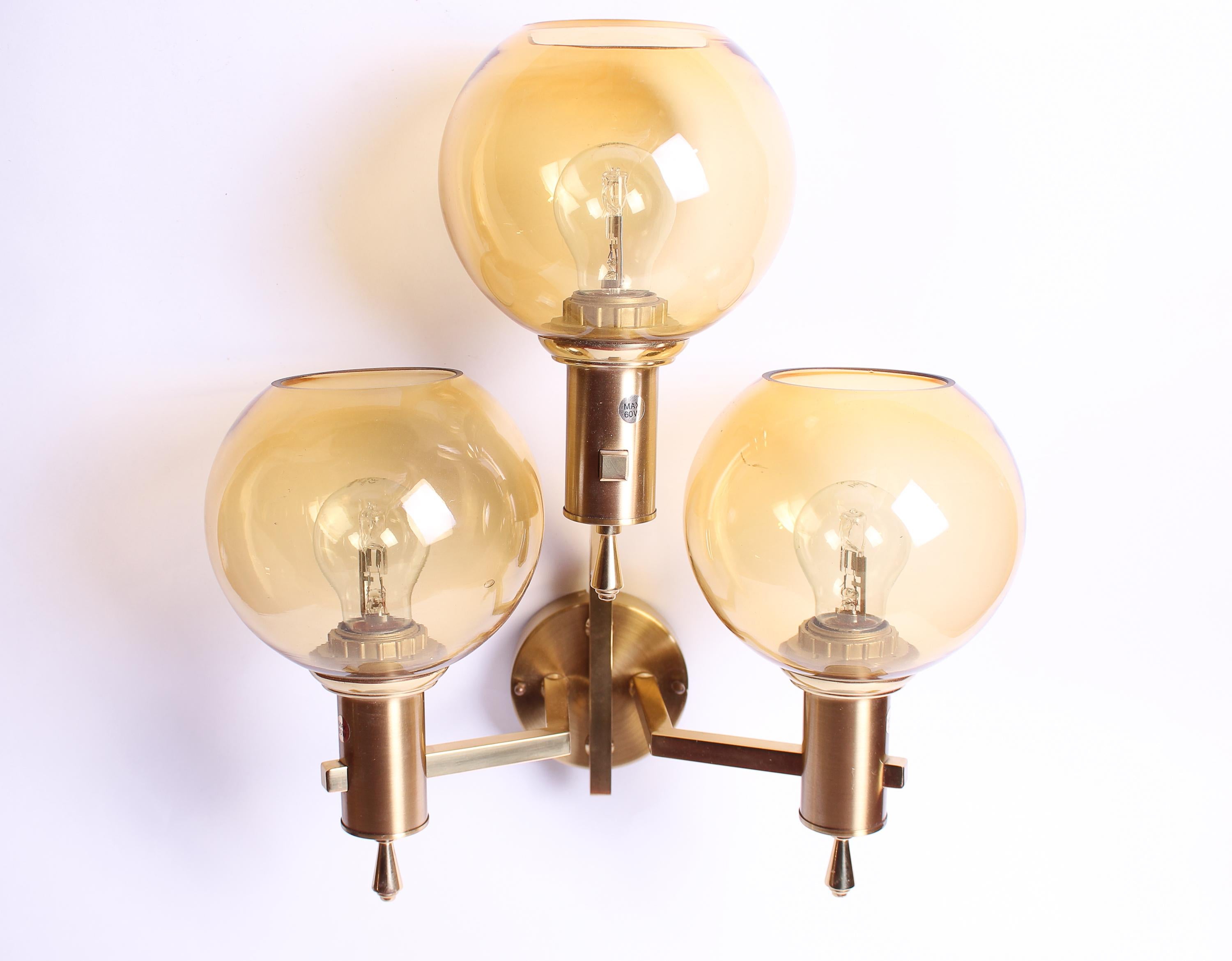 Two mid-century wall lamps produced by EWÅ Värnamo. The lamps are made out of brass with round glass shades. Excellent vintage condition with signs of usage consistent with age. Two available.