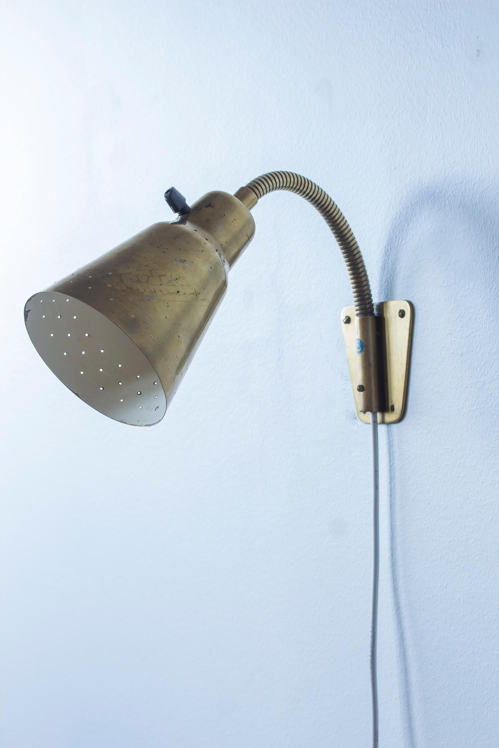 Pair of wall lamps attributed to Eje Ahlgren. Produced in Sweden by Bergboms during the 1950s. High quality thick brass with perforated shades and adjustable arms. Can be used both as reading light or uplight. Original bakelite turn light switches