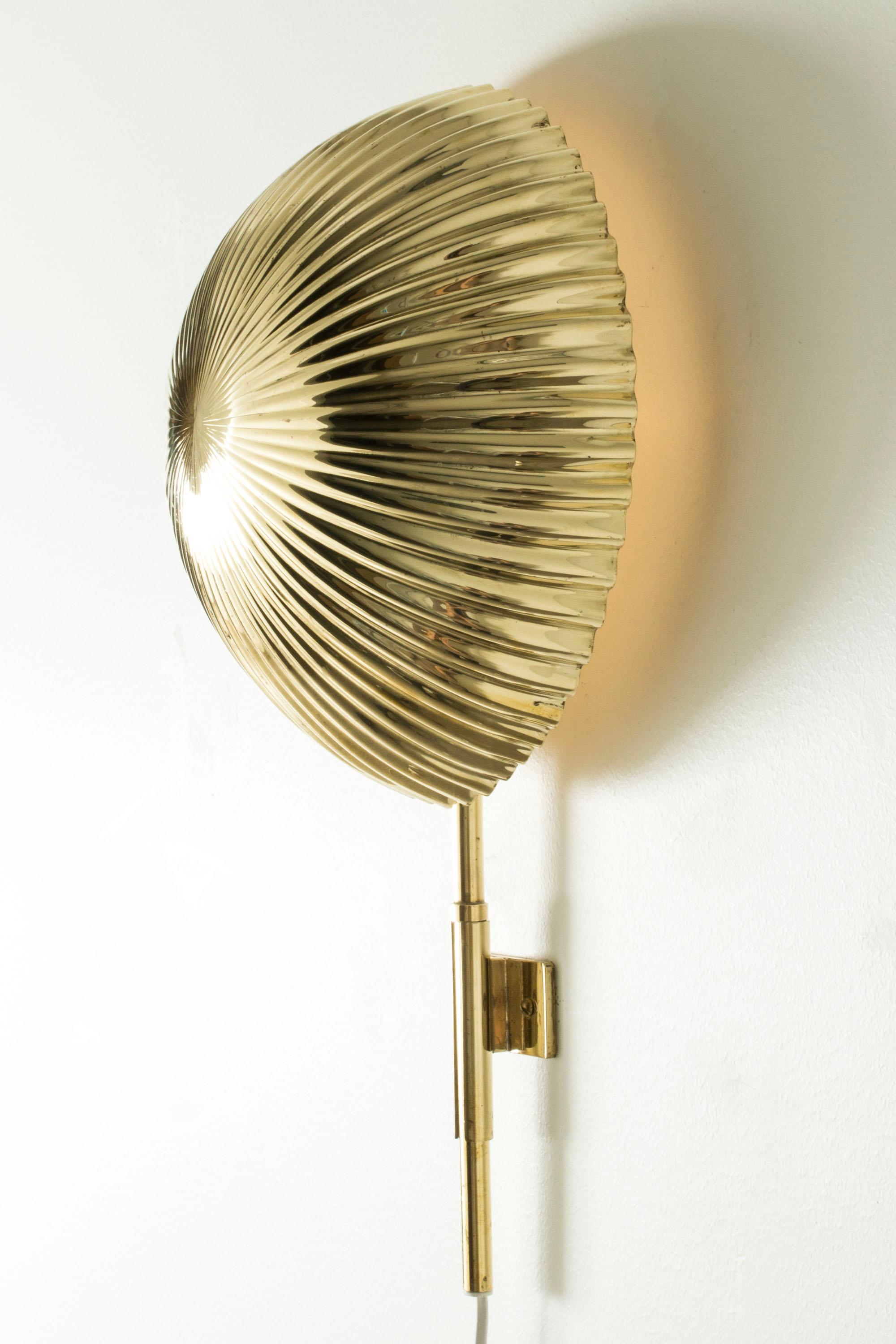 Raro y hermoso aplique de Paavo Tynell, fabricado en latón. Forma de concha grande y redonda con bordes festoneados orientados hacia la pared y que crean un hermoso brillo que emana a su alrededor.