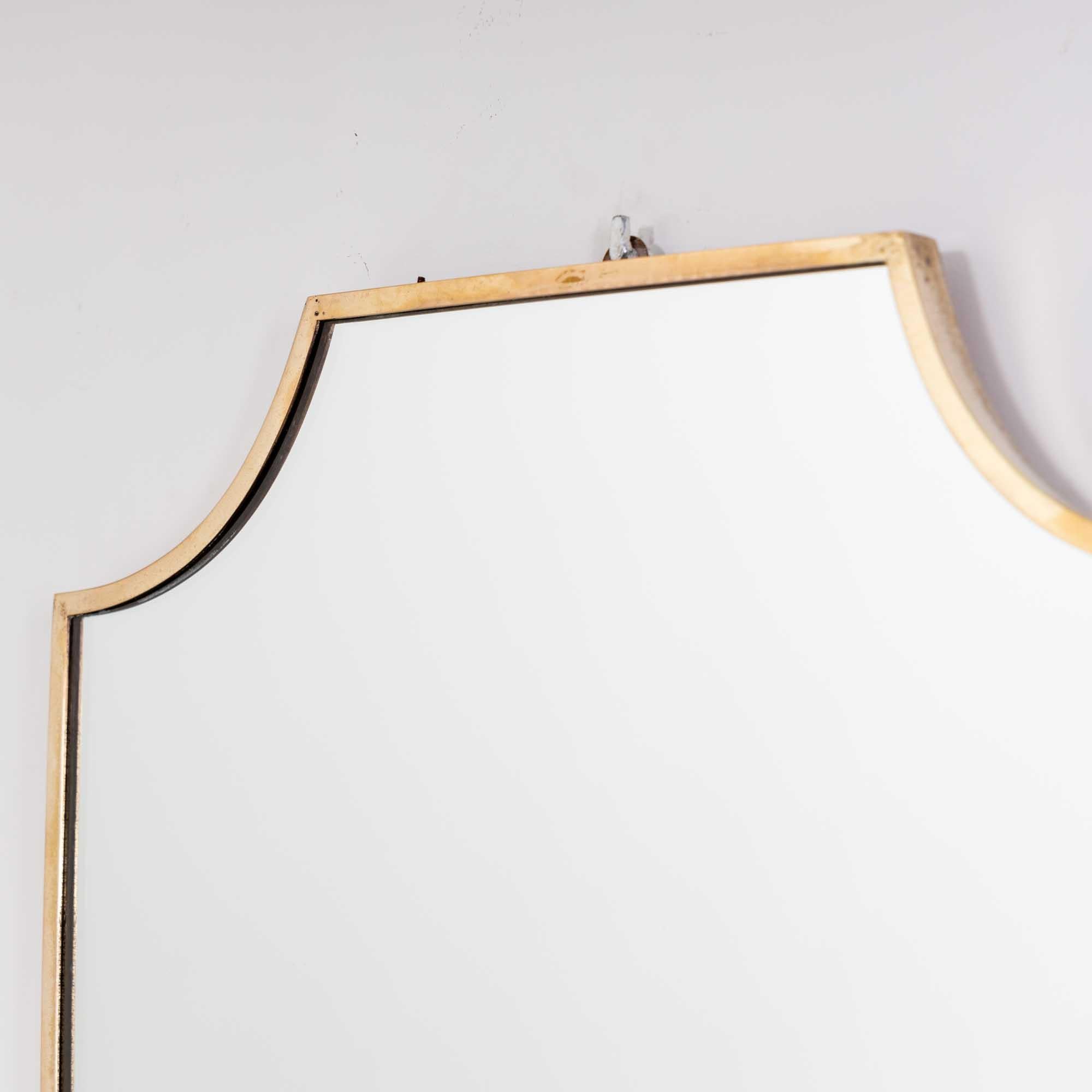 Shield-shaped wall mirror with a slim brass frame in the style of Gio Ponti. 
This mirror is of a convenient and practical size, making it the perfect vanity mirror.