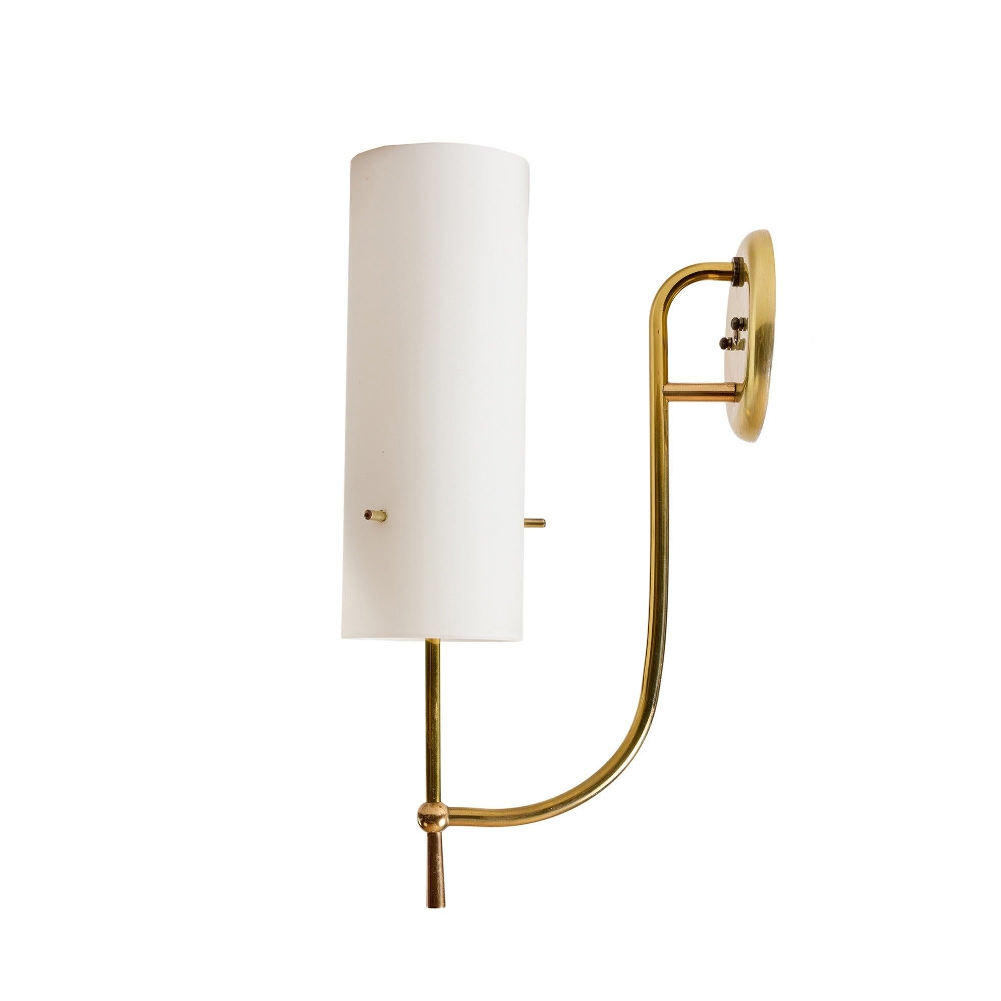 Un sofisticado candelabro de latón sobre una elegante varilla curva, con una pantalla de cristal blanco, sujeta por tres varillas de latón que atraviesan el cristal.