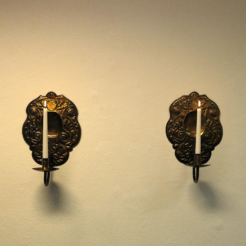 A lovely mid-century brass wall lamp pair with decorated brass back plate designed and handmade by Lars Holmström, Arvika - Sweden 1950s. These sconces are for wall hanging and gives a beautiful shine when candles are lit. Marked with Lars