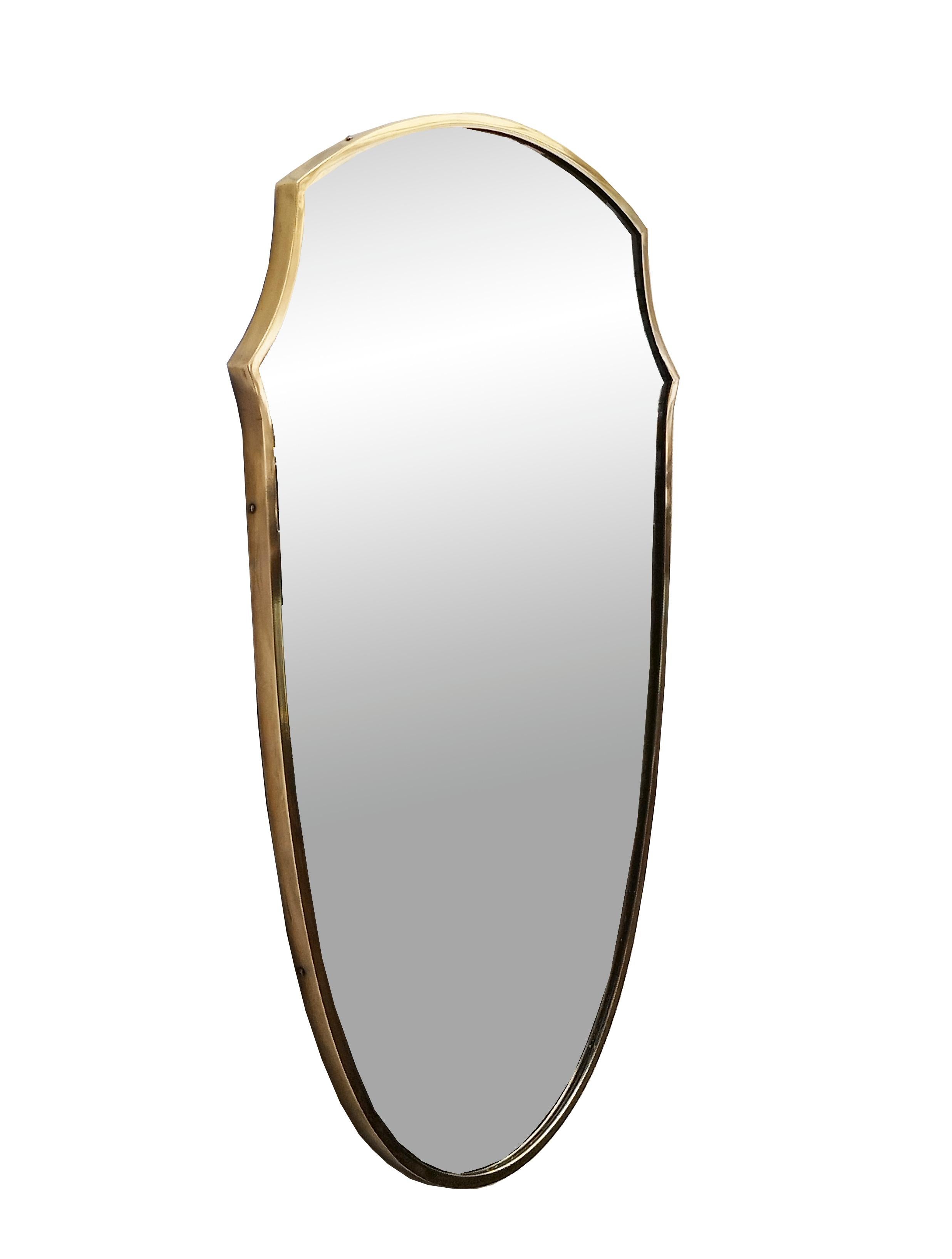 Solid brass shield wall mirror designed and manufactured in Italy in the 1950s, the brass is in original patina, the original mirror glass is in perfect condition.