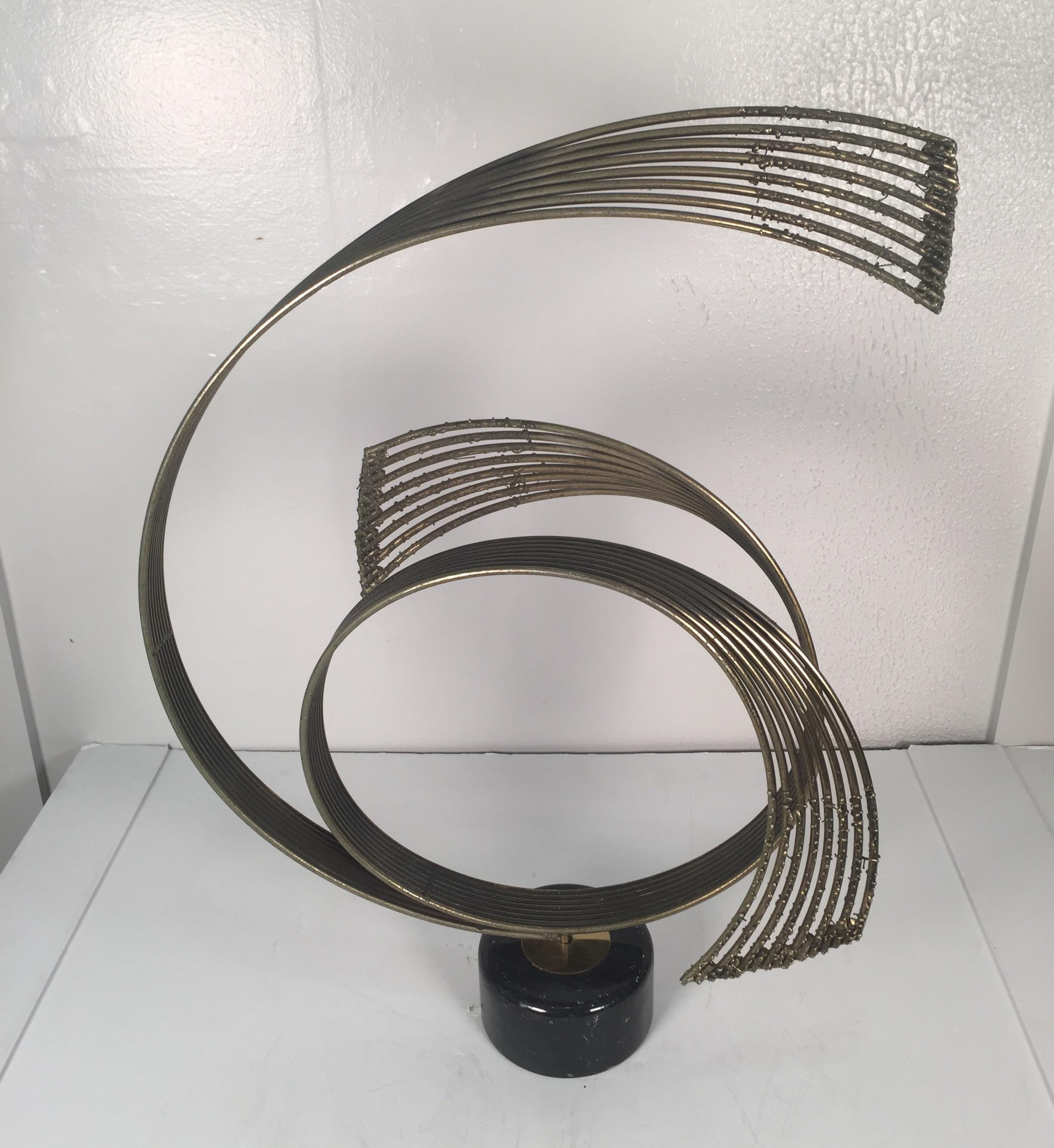 An abstract steel and brass sculpture on a marble base by C. Jere.