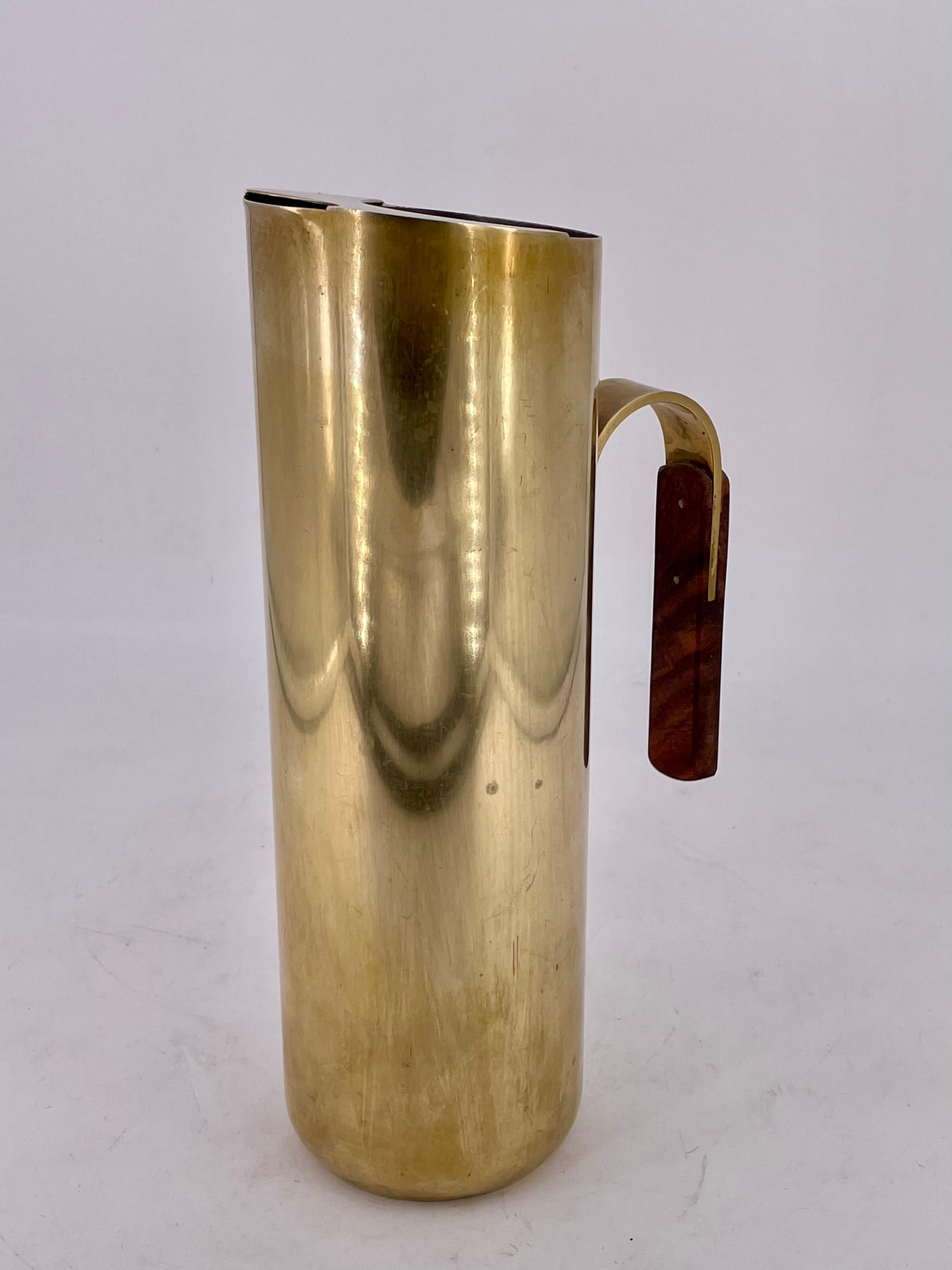 Polished brass Italian water pitcher circa 1950s, with silver lining and a rosewood handle circa 1950s, some patina tall unique and elegant piece stamped on the bottom made in Italy.