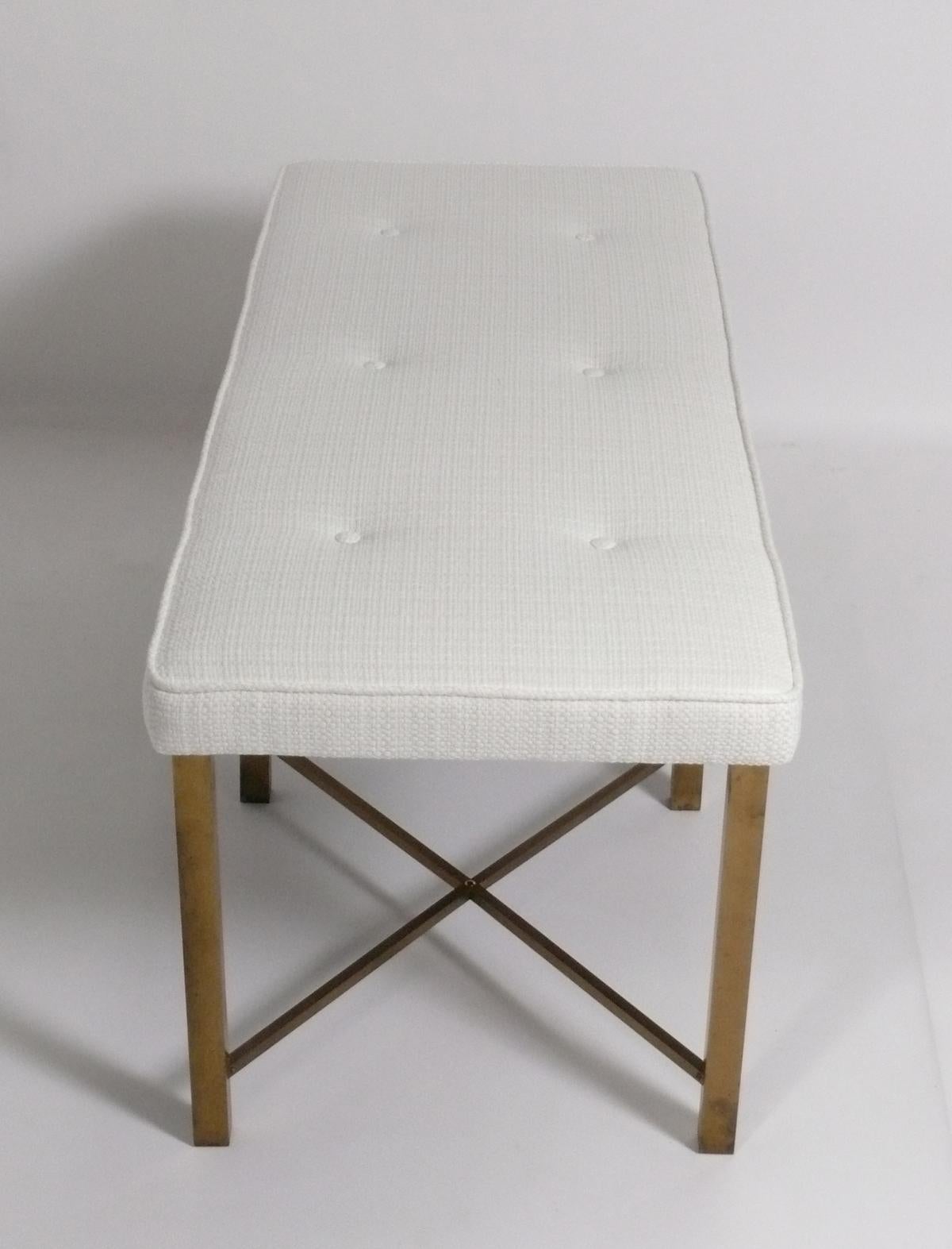 Brass X form bench, American, circa 1950s. This bench has been recently reupholstered in an ivory color boucle fabric. The brass base retains its original warm patina.