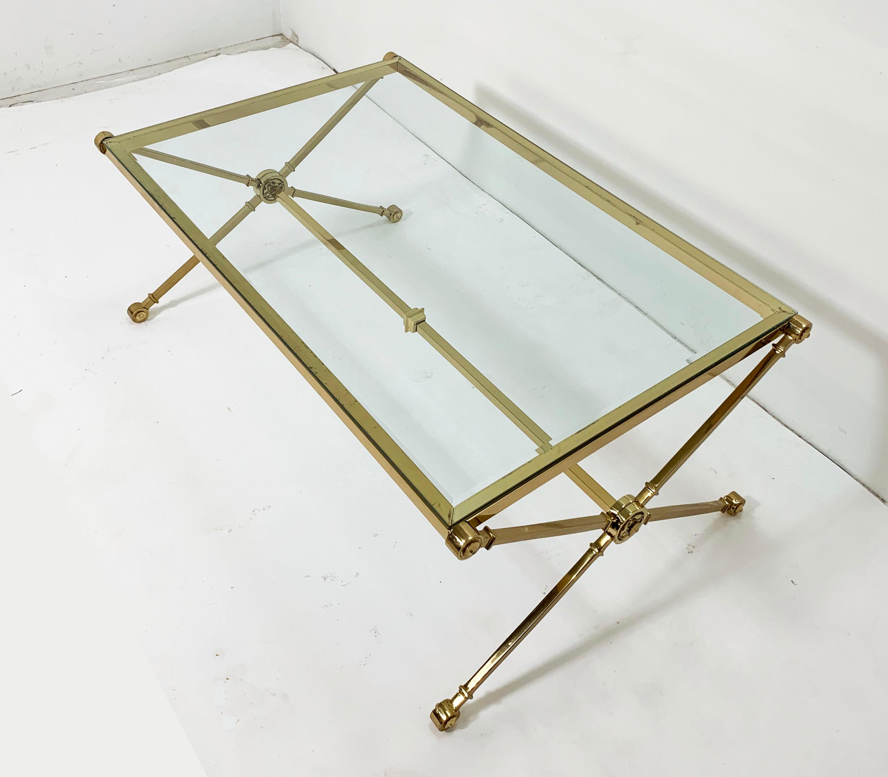 Brass coffee table with x-form base accentuated with medallions, in the manner of Maison Jansen, circa 1960s.