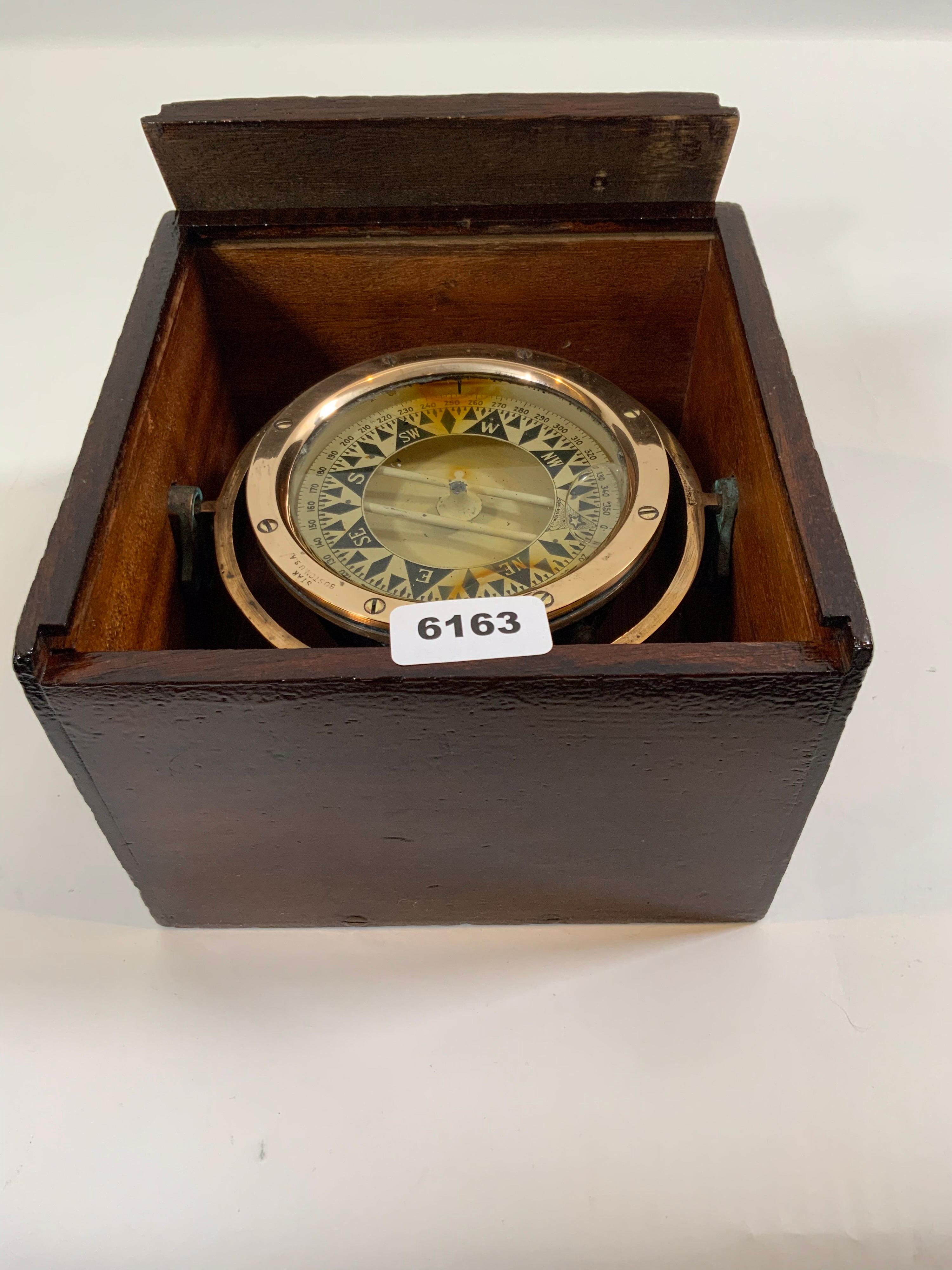 Gimballed brass boat compass fitted to a varnished wood box with sliding lid. Compass card is marked with maker's name 