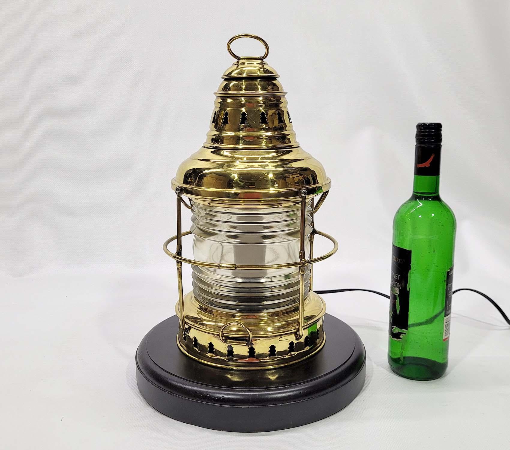 Solid brass marine lantern with Fresnel glass lens. Protective brass cage. This lantern has been meticulously polished and lacquered. It has been wired with a new socket and mounted to a thick wood base with rich finish. Beautiful finish. Circa