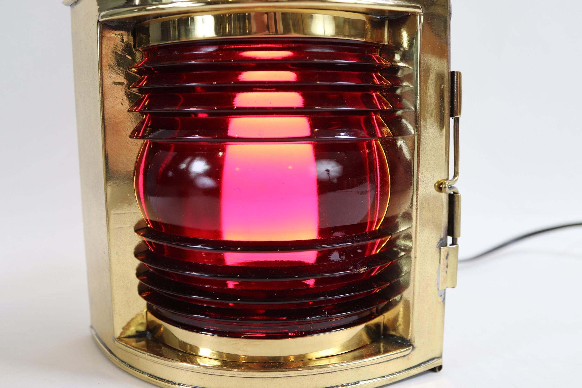 Highly polished and lacquered ship lantern with large hoop handle, hinged door, vented top and electric socket for home display. Plate on top reads 