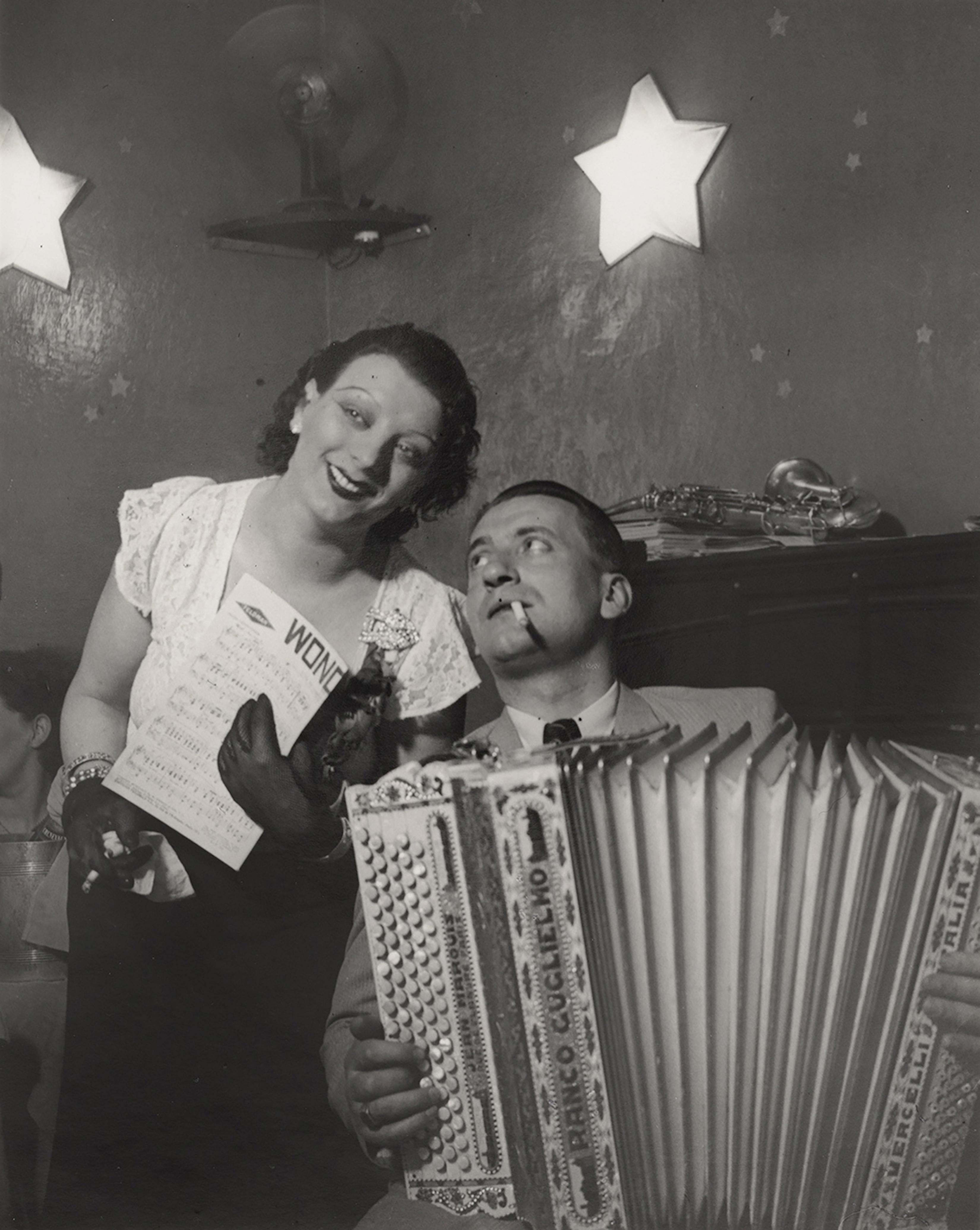 Brassaï Black and White Photograph - Kiki avec son accordéoniste, au Cabaret des fleurs, à Montparnasse